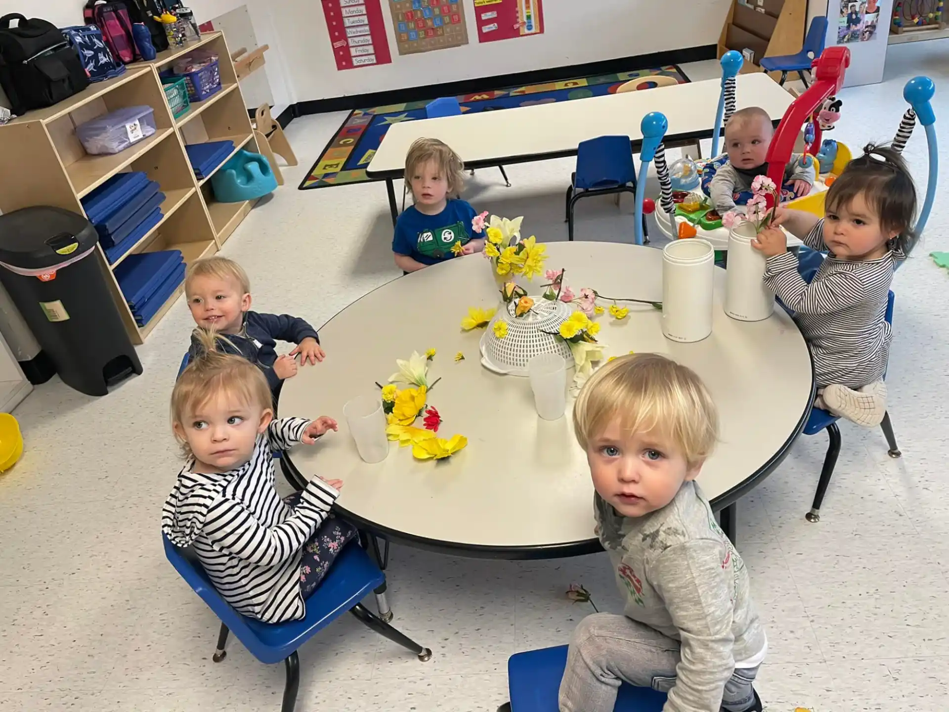 a group of children sitting around a table with flowers