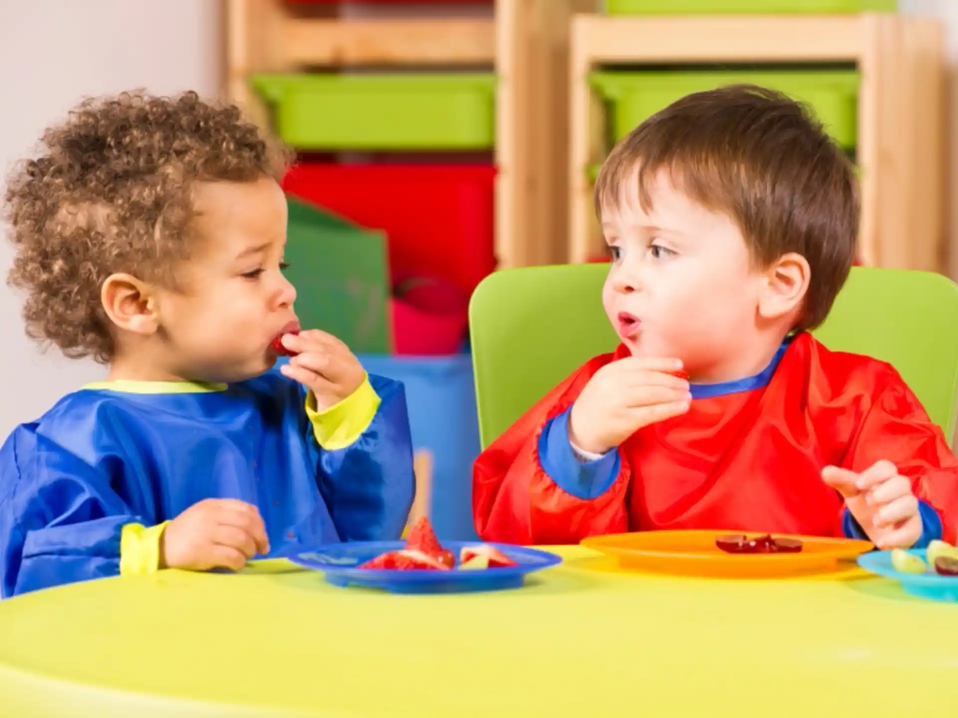 a couple of young boys eating at a table