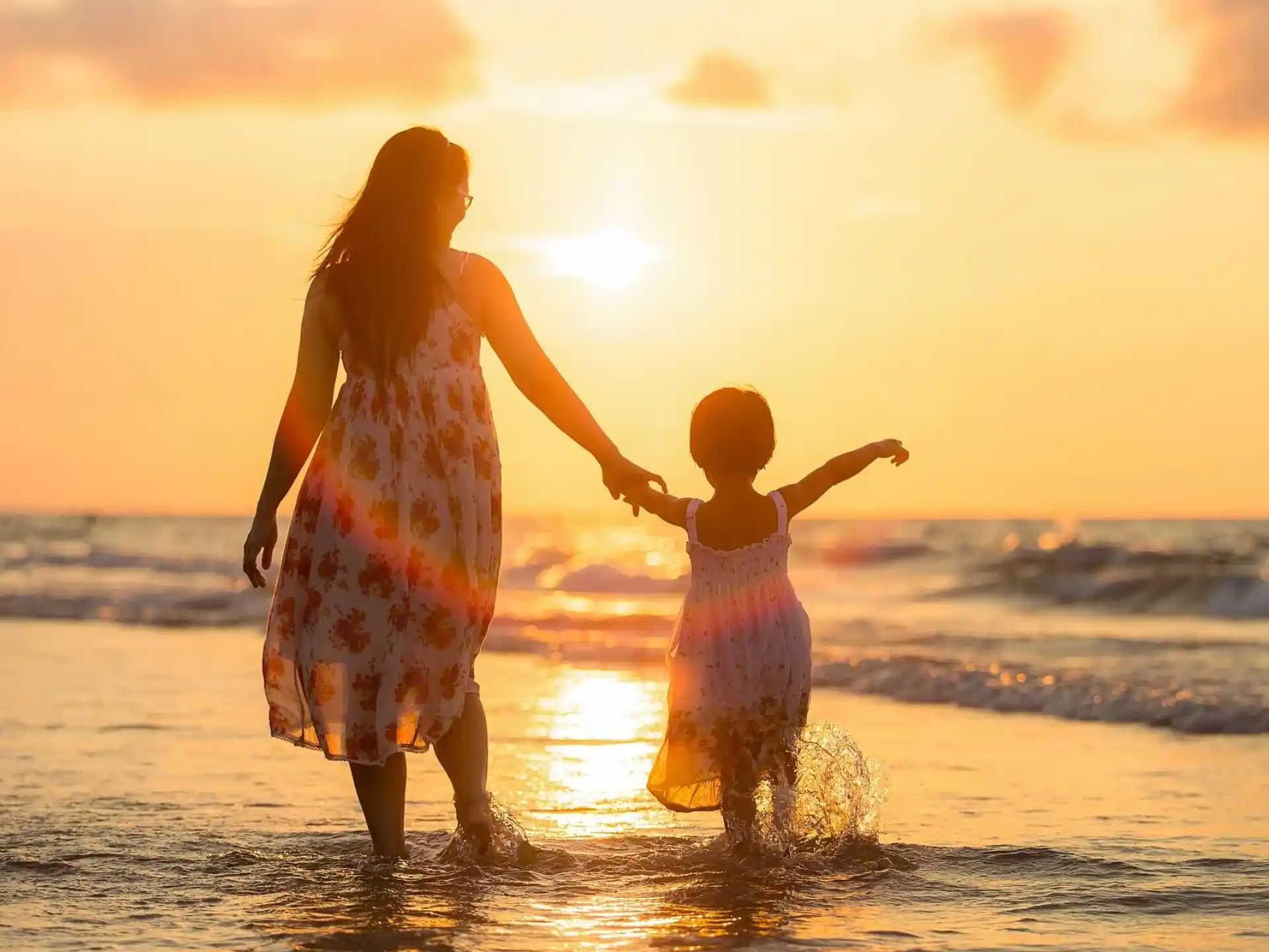 a man and a child holding hands and walking on the beach