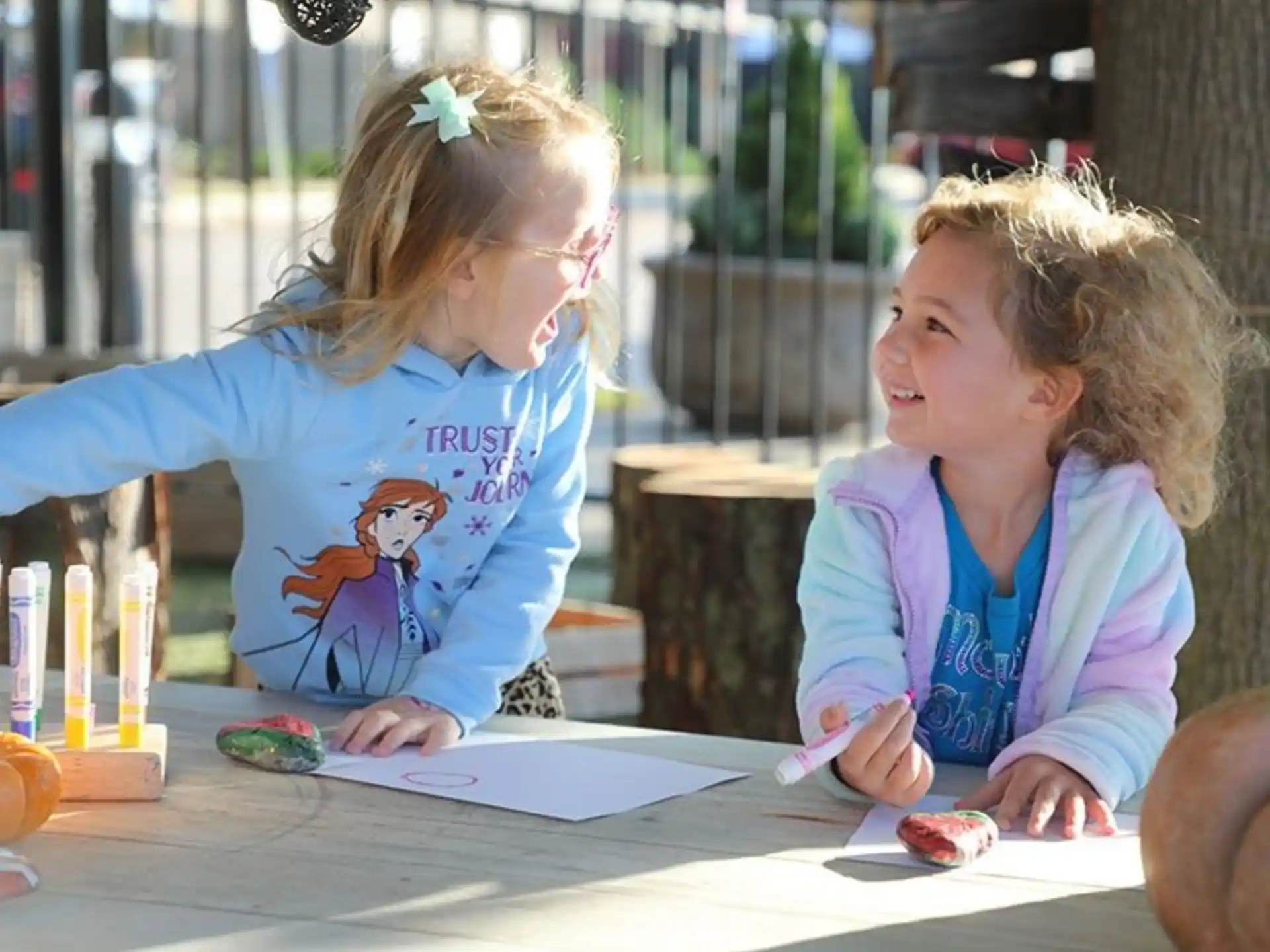 a couple of young girls sitting at a table looking at a paper