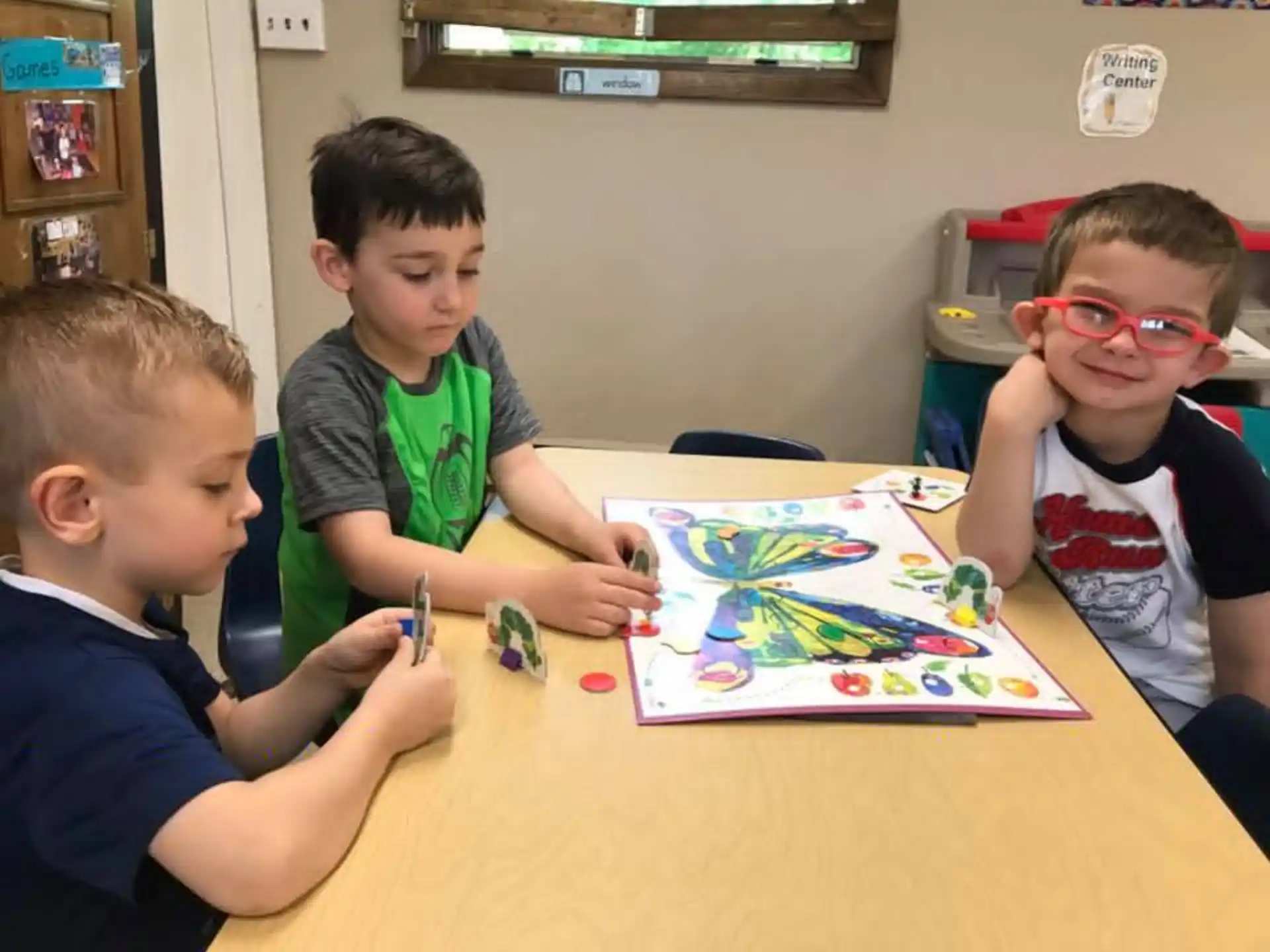a group of boys sitting at a table playing a board game