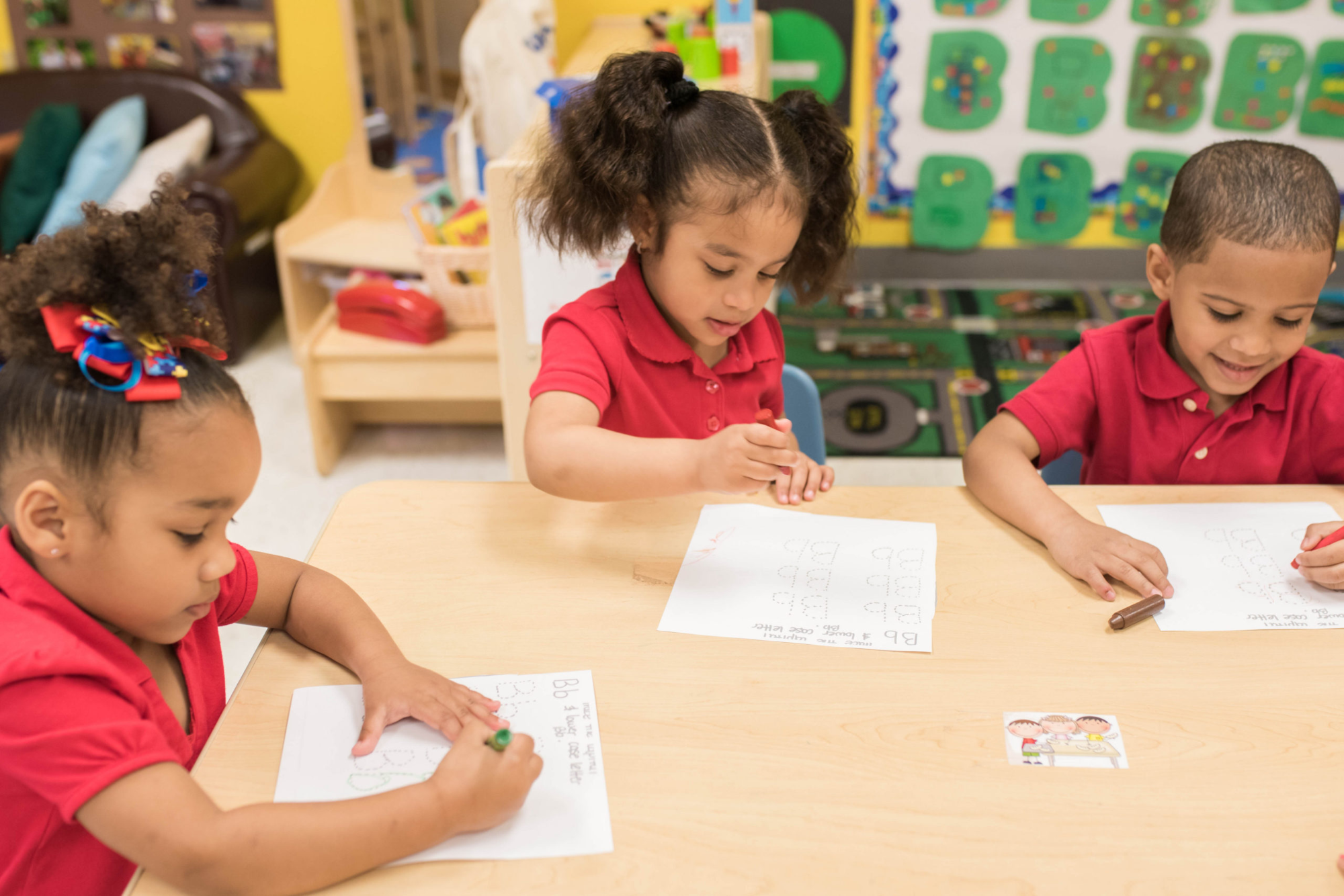 a group of children sitting at a table writing on paper