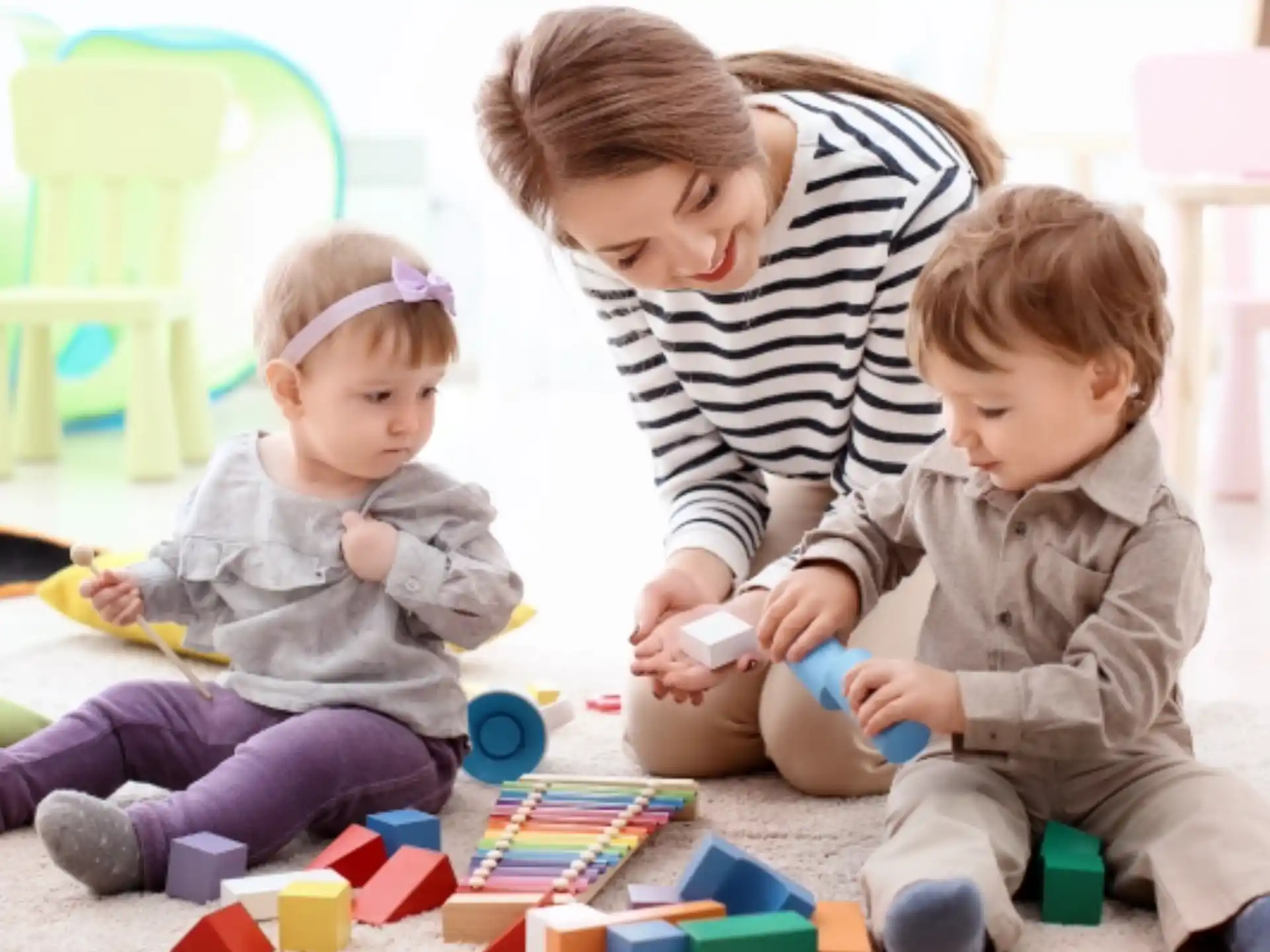 a person and two children playing with toys on the floor