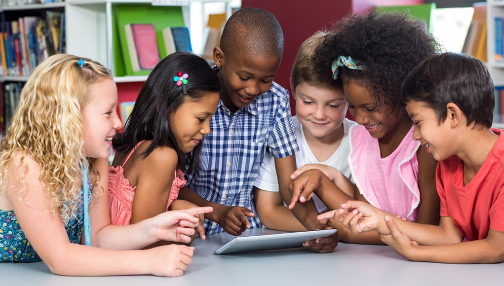 a group of children looking at a tablet