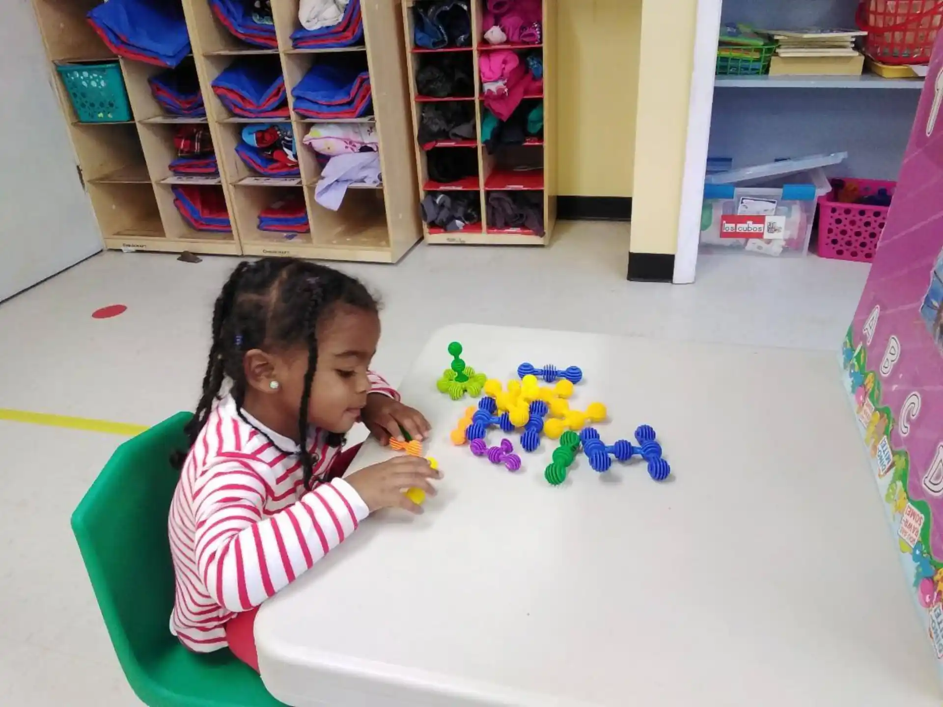 a girl sitting at a table with a toy