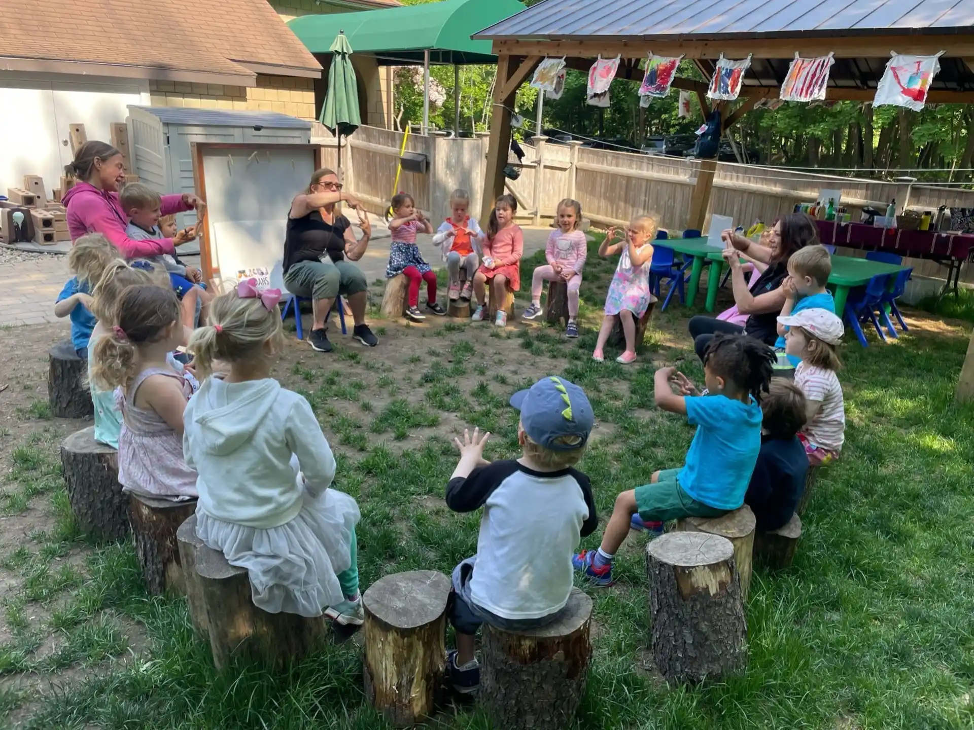 a group of children sitting on stumps in a grassy area