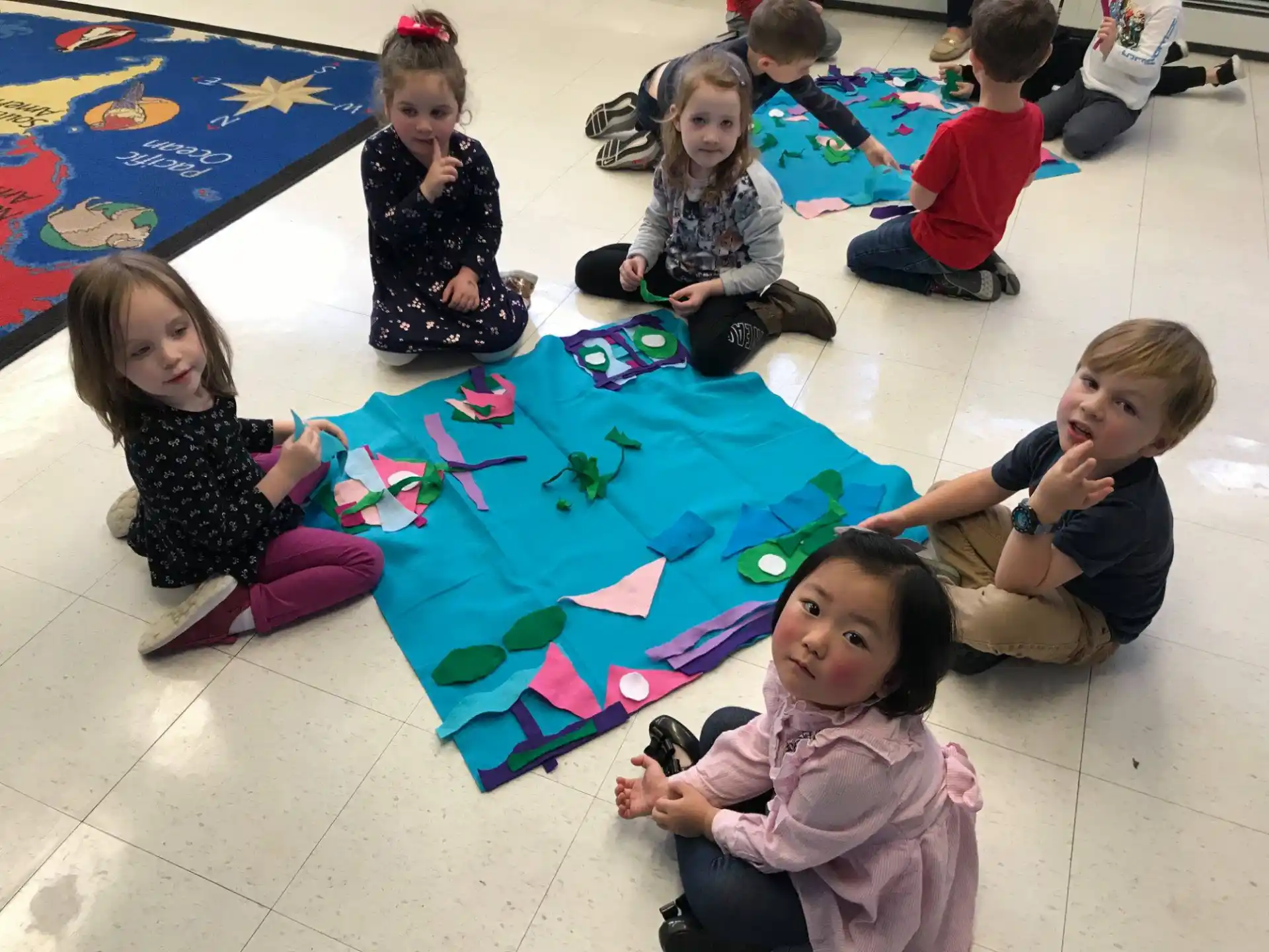 a group of children sitting on the floor with a kite