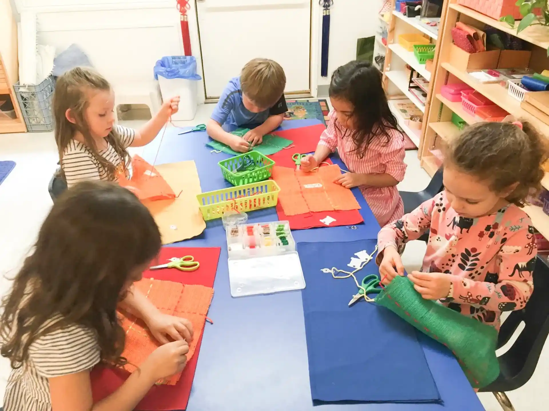 a group of children sitting at a table with colorful paper on it