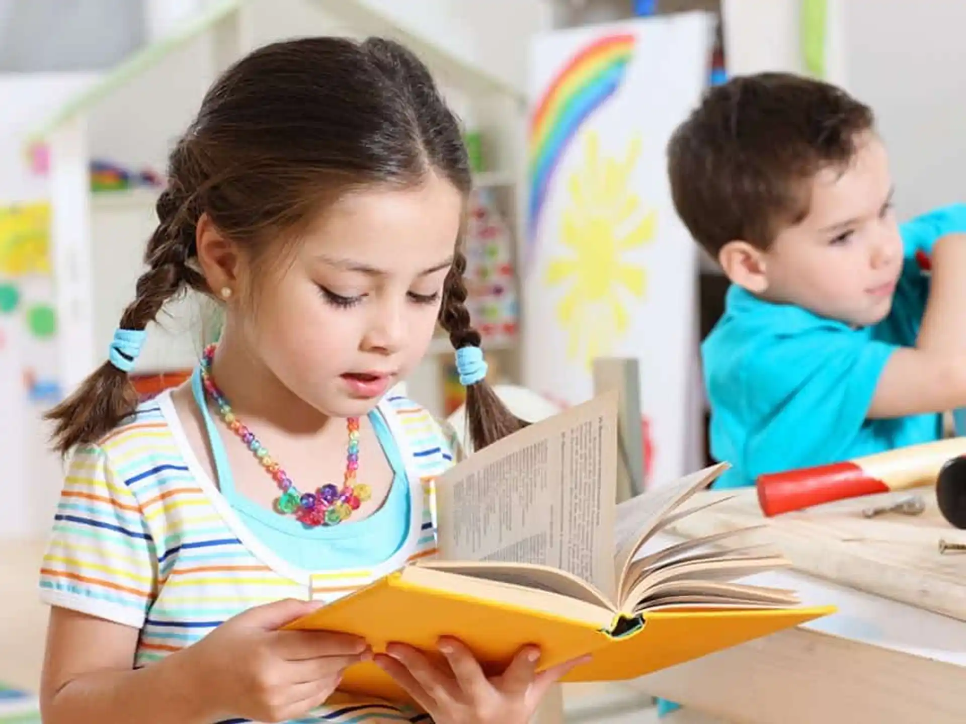 a young girl and a young boy reading a book