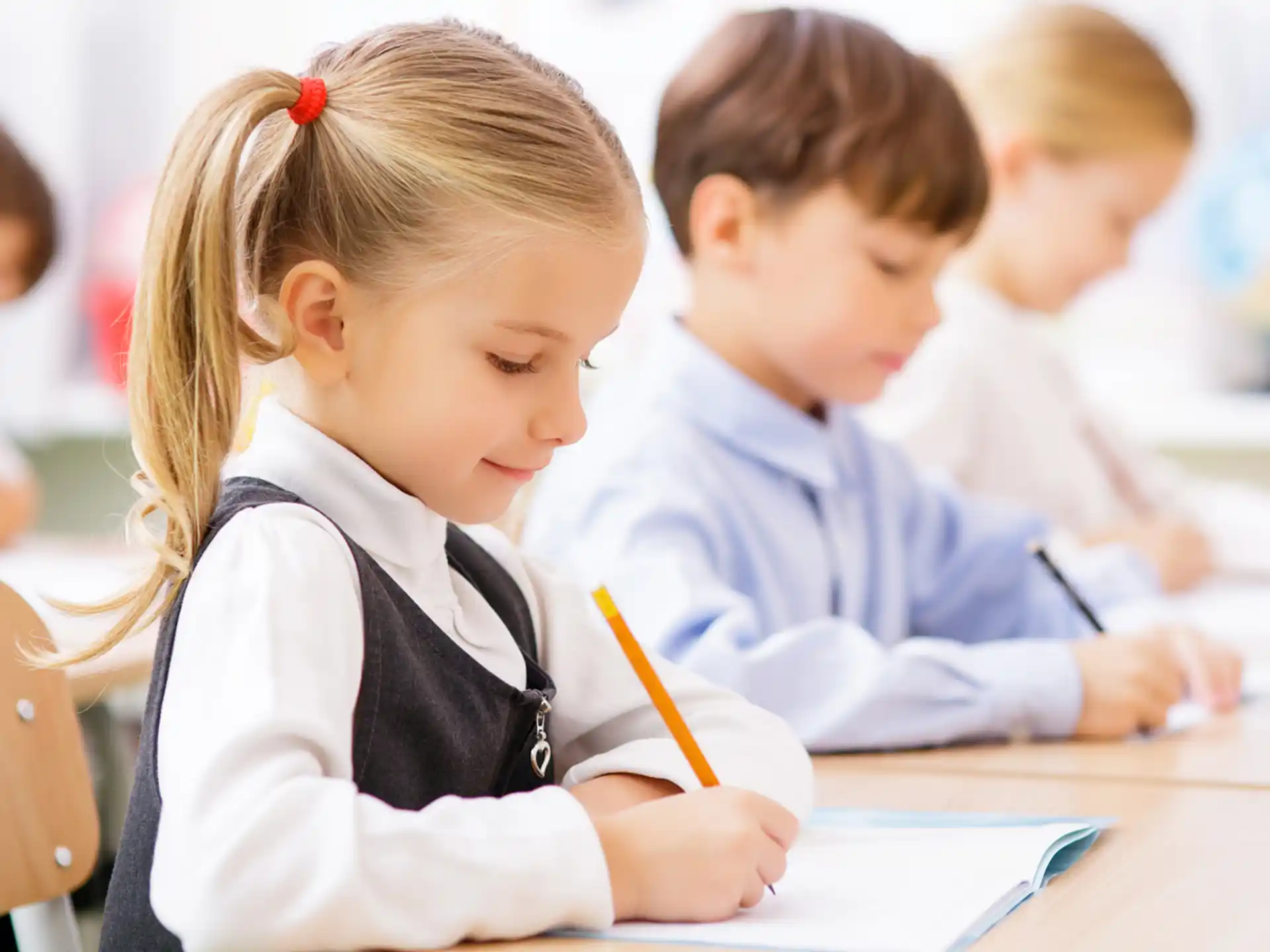 a group of children sitting at a table writing on paper