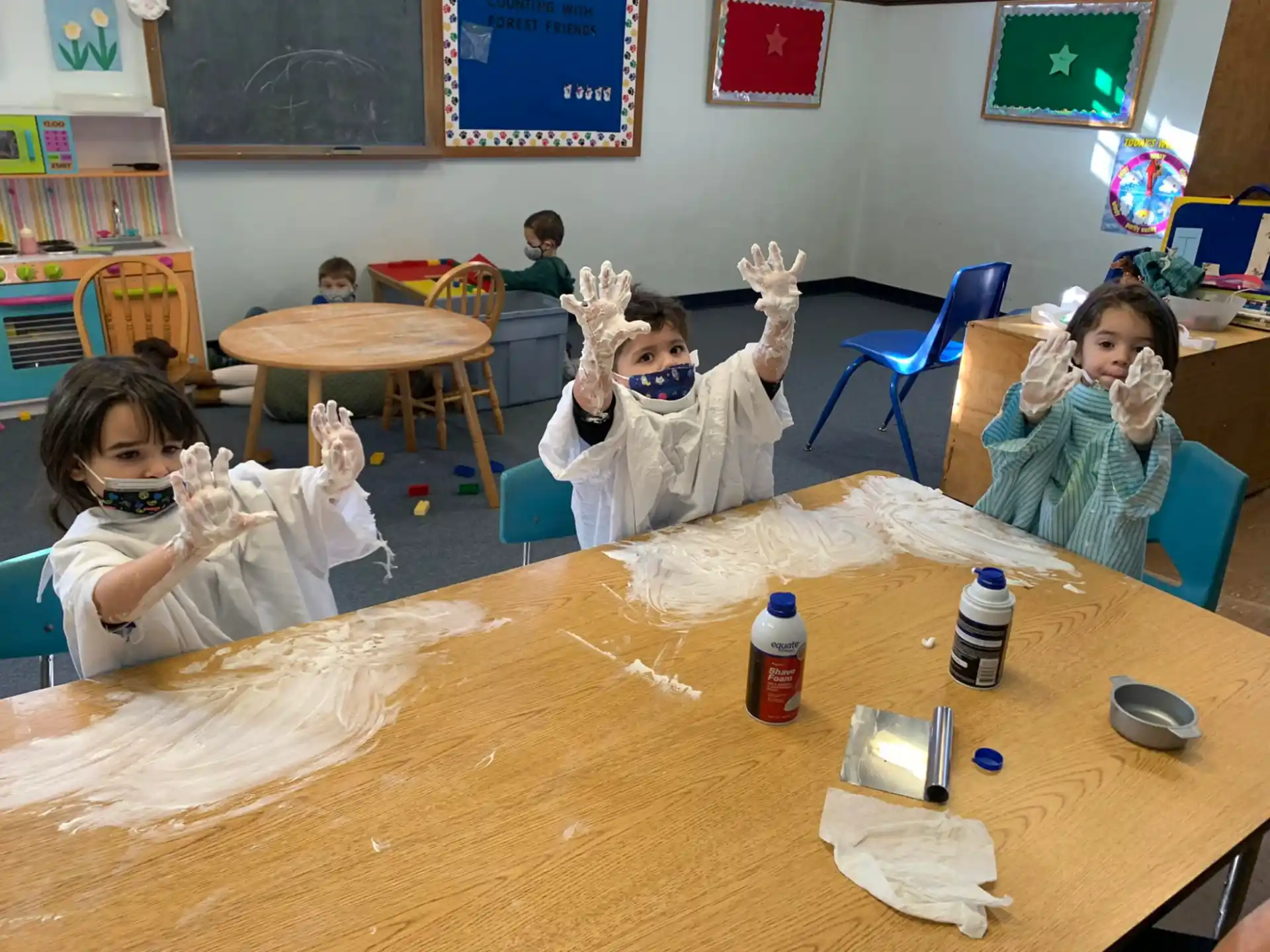 a group of children sitting at a table in a classroom