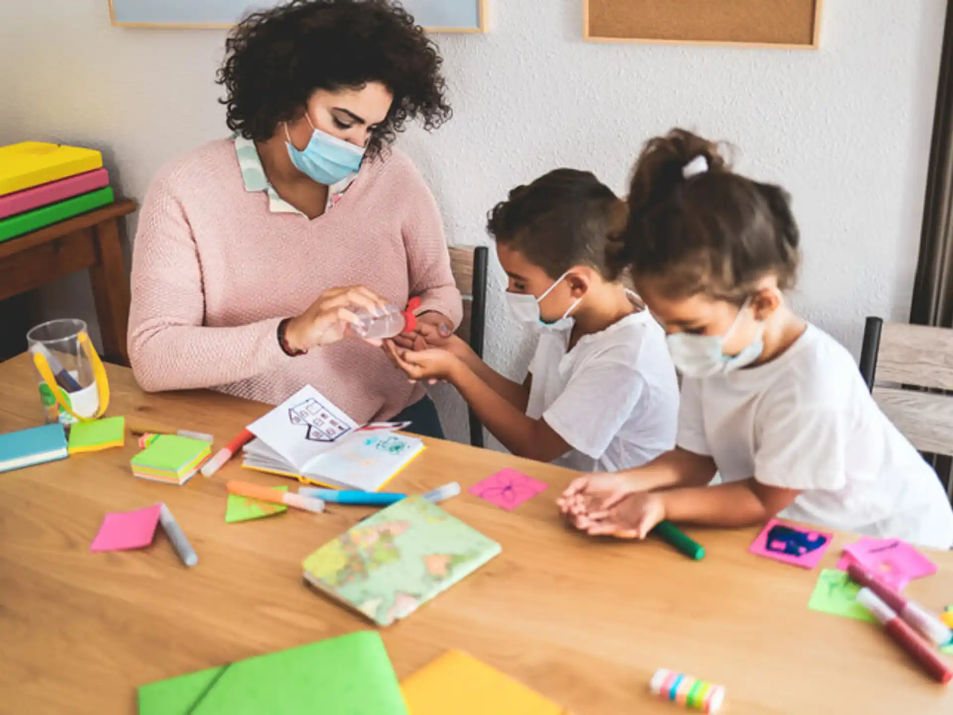a person and two children playing with colorful paper on a table
