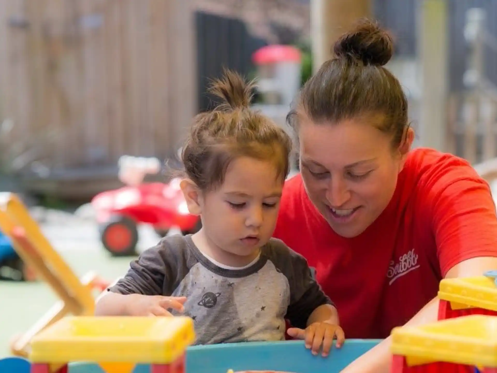 a person and a child playing with a toy car