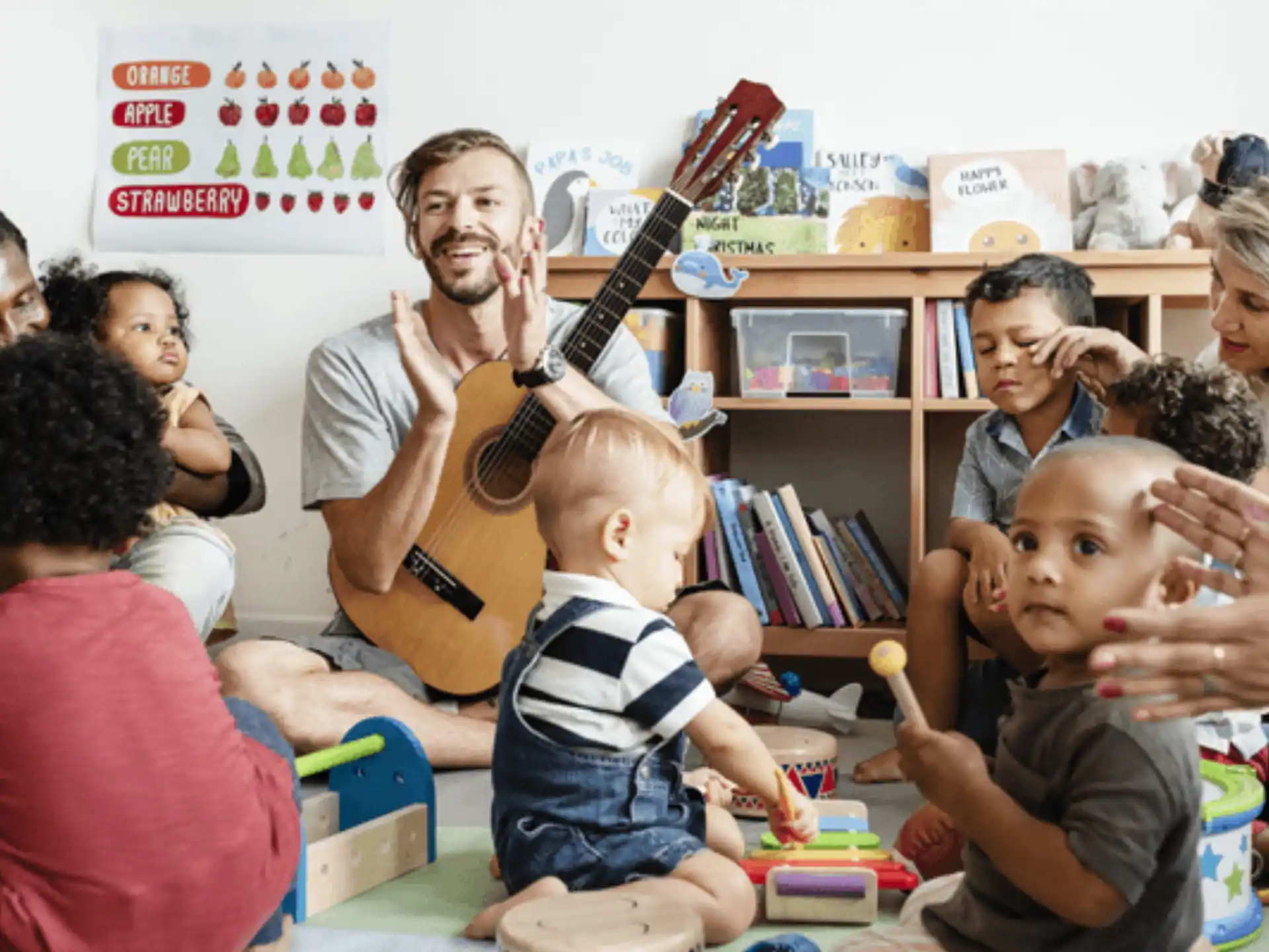 a person playing guitar in front of a group of children