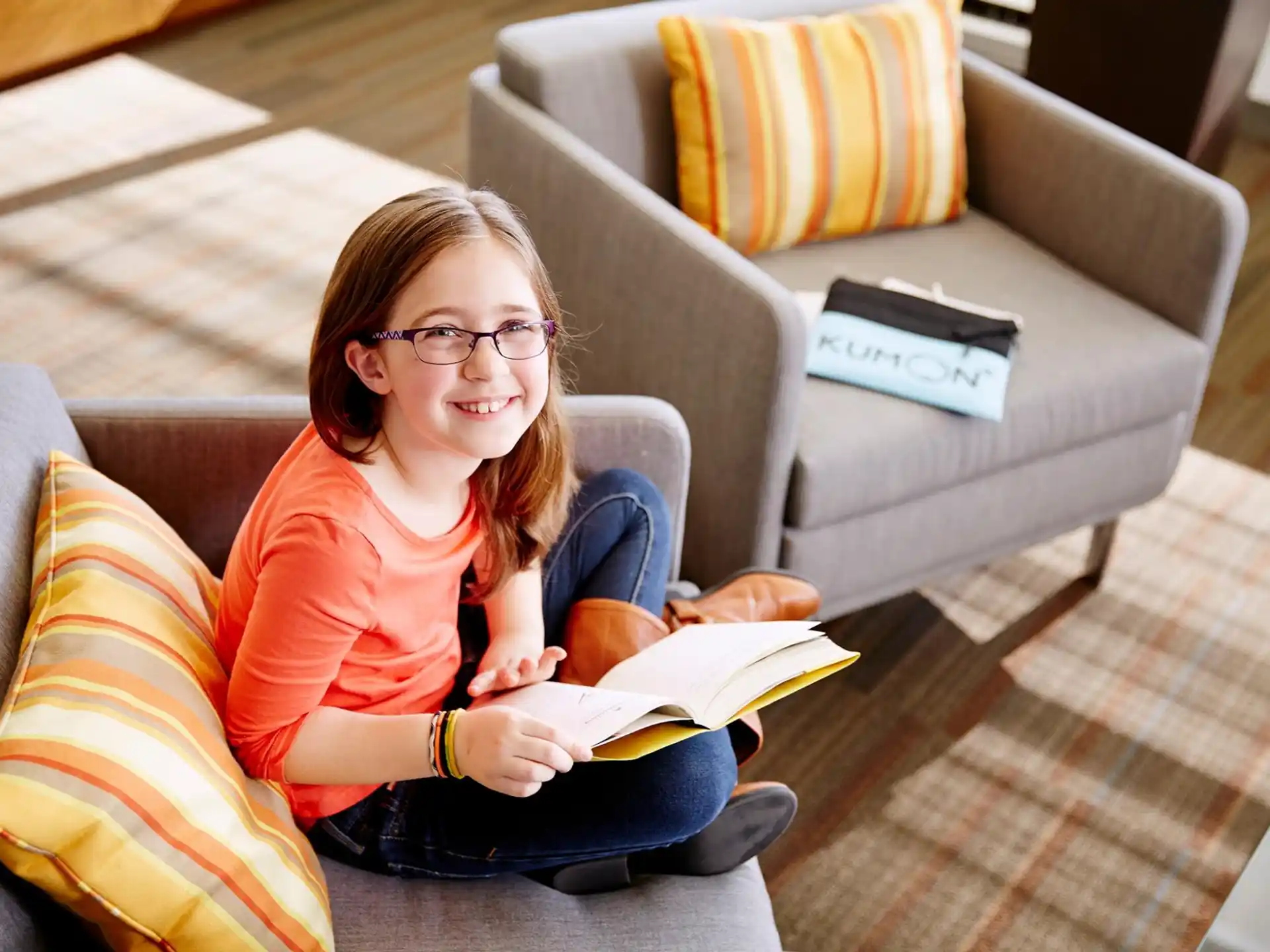 a girl sitting on a couch reading a book