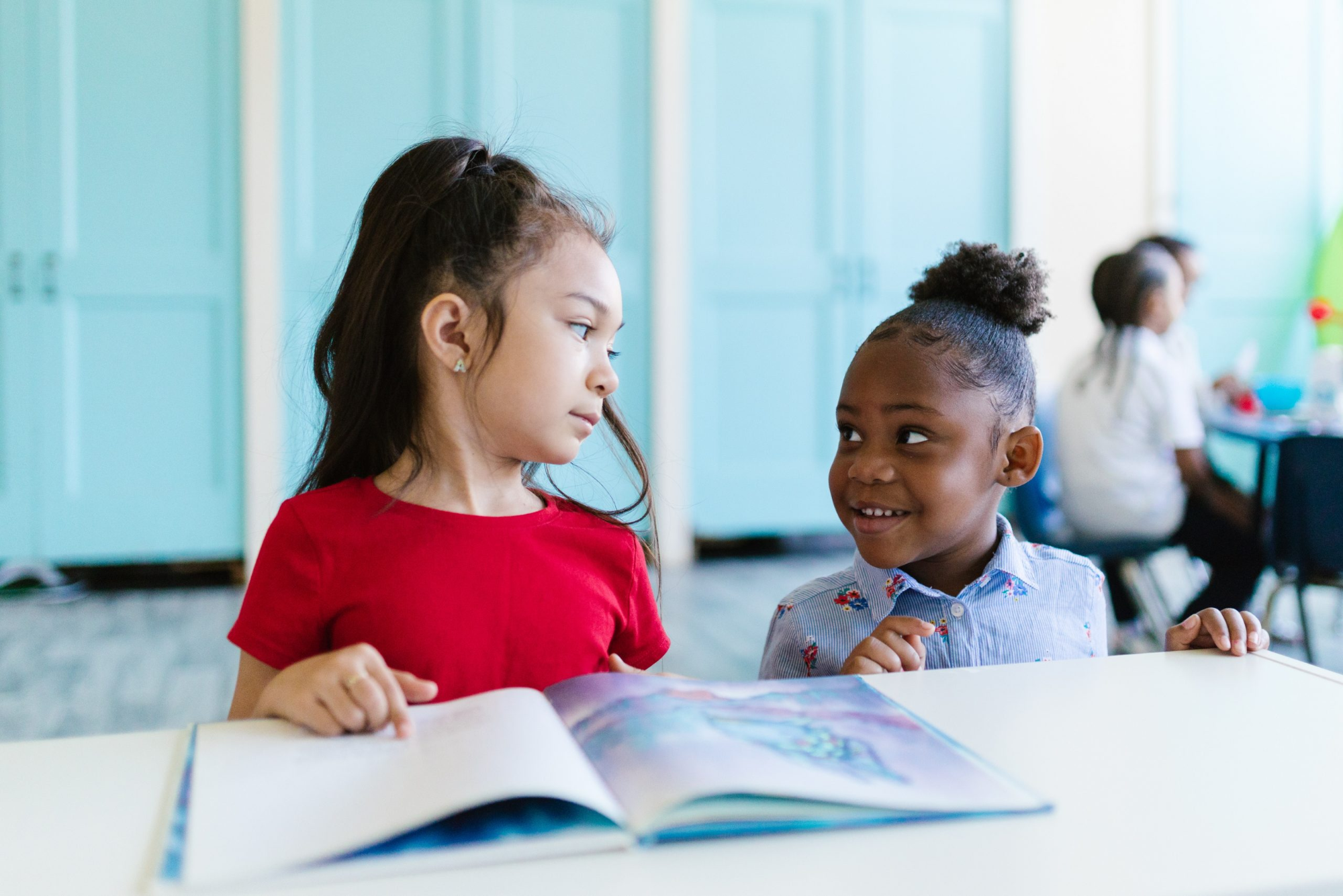 a young girl and a young boy reading a book