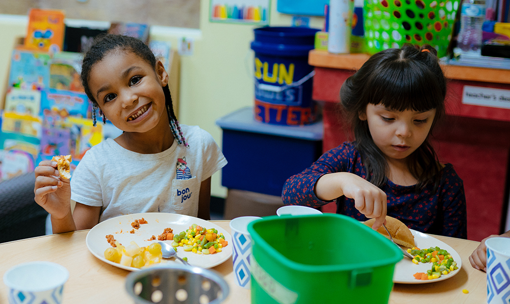 a couple of young girls eating at a table