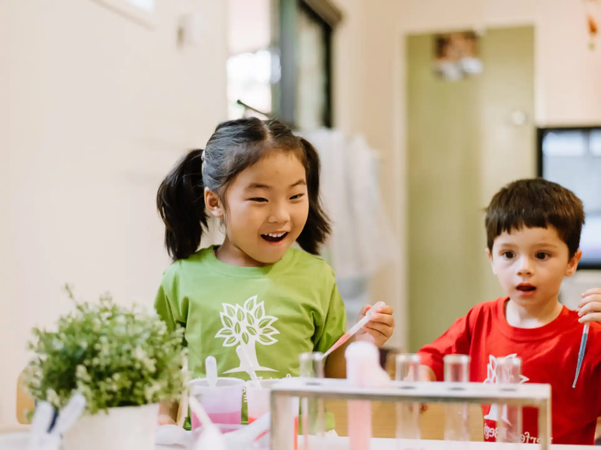 a couple of children sitting at a table with cups and straws