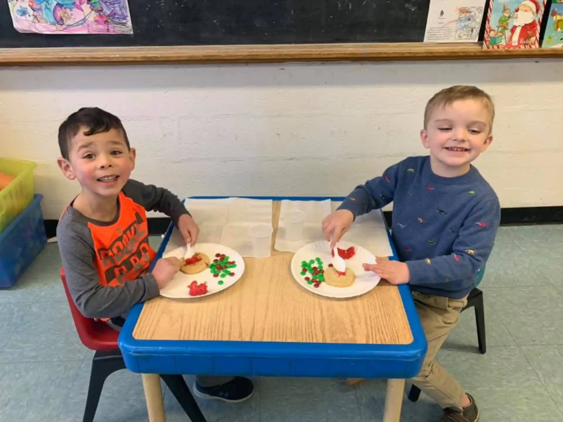 two boys sitting at a table with food on it