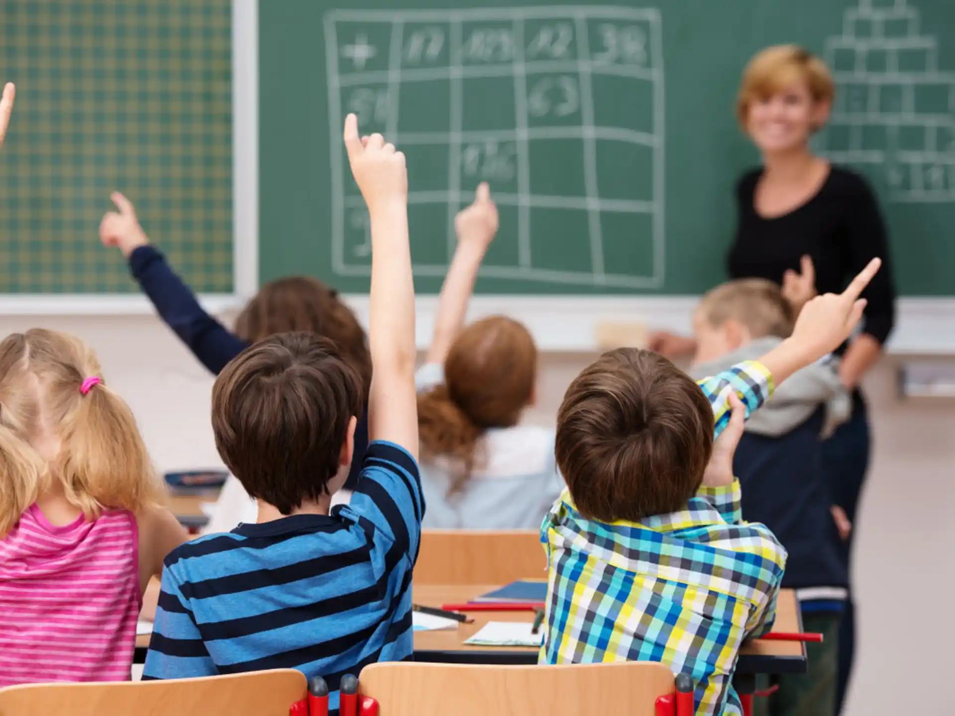 a group of children raising their hands