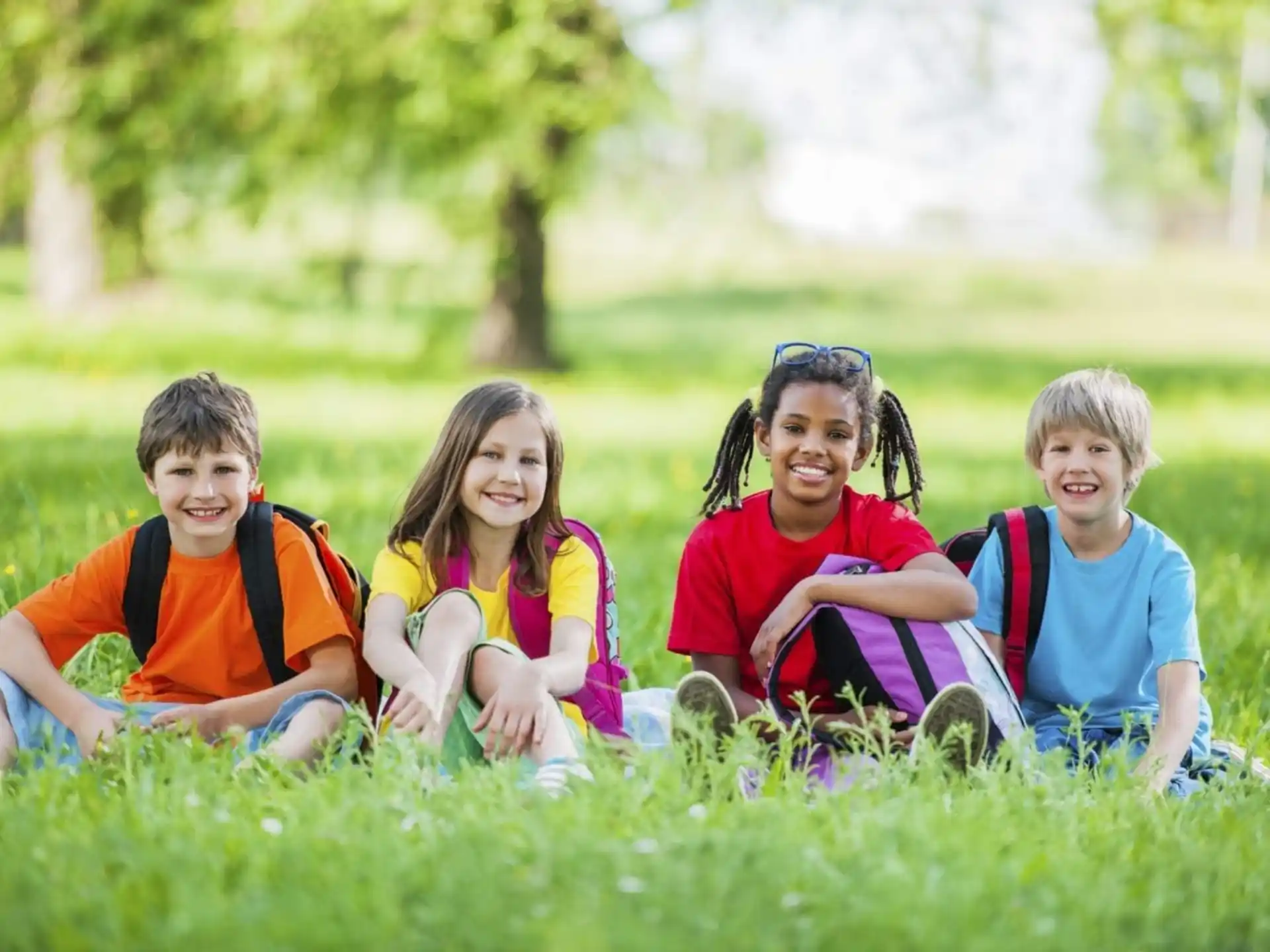 a group of children sitting in the grass