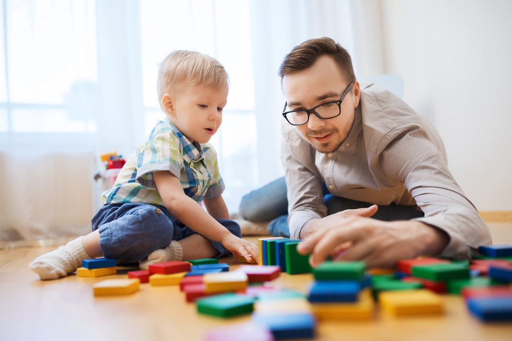 a person and a baby playing with blocks on the floor