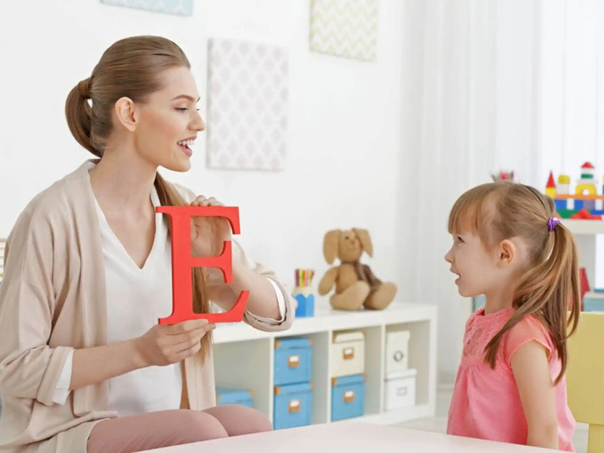 a woman holding a gift box to a little girl
