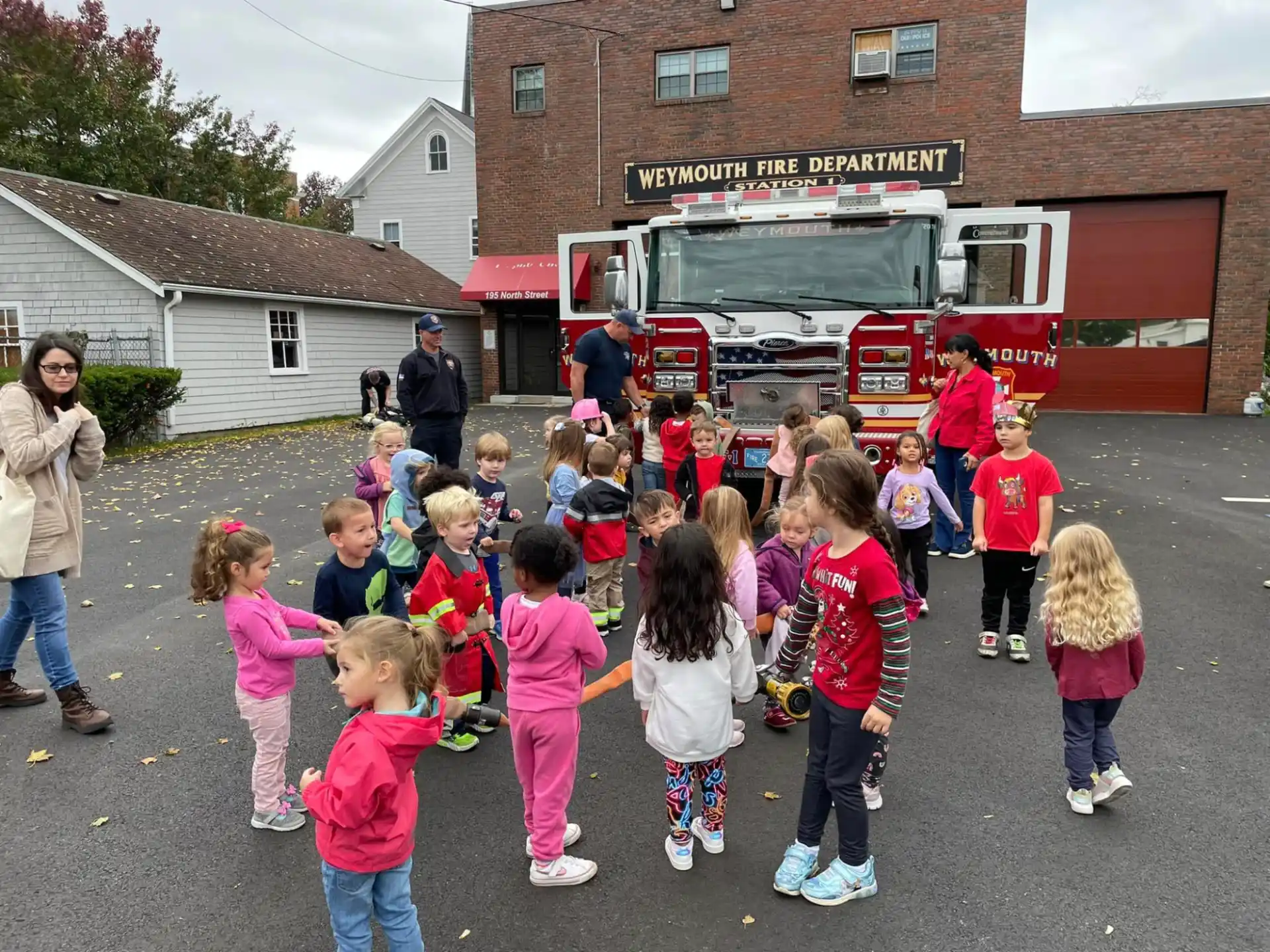 a group of children standing in front of a firetruck