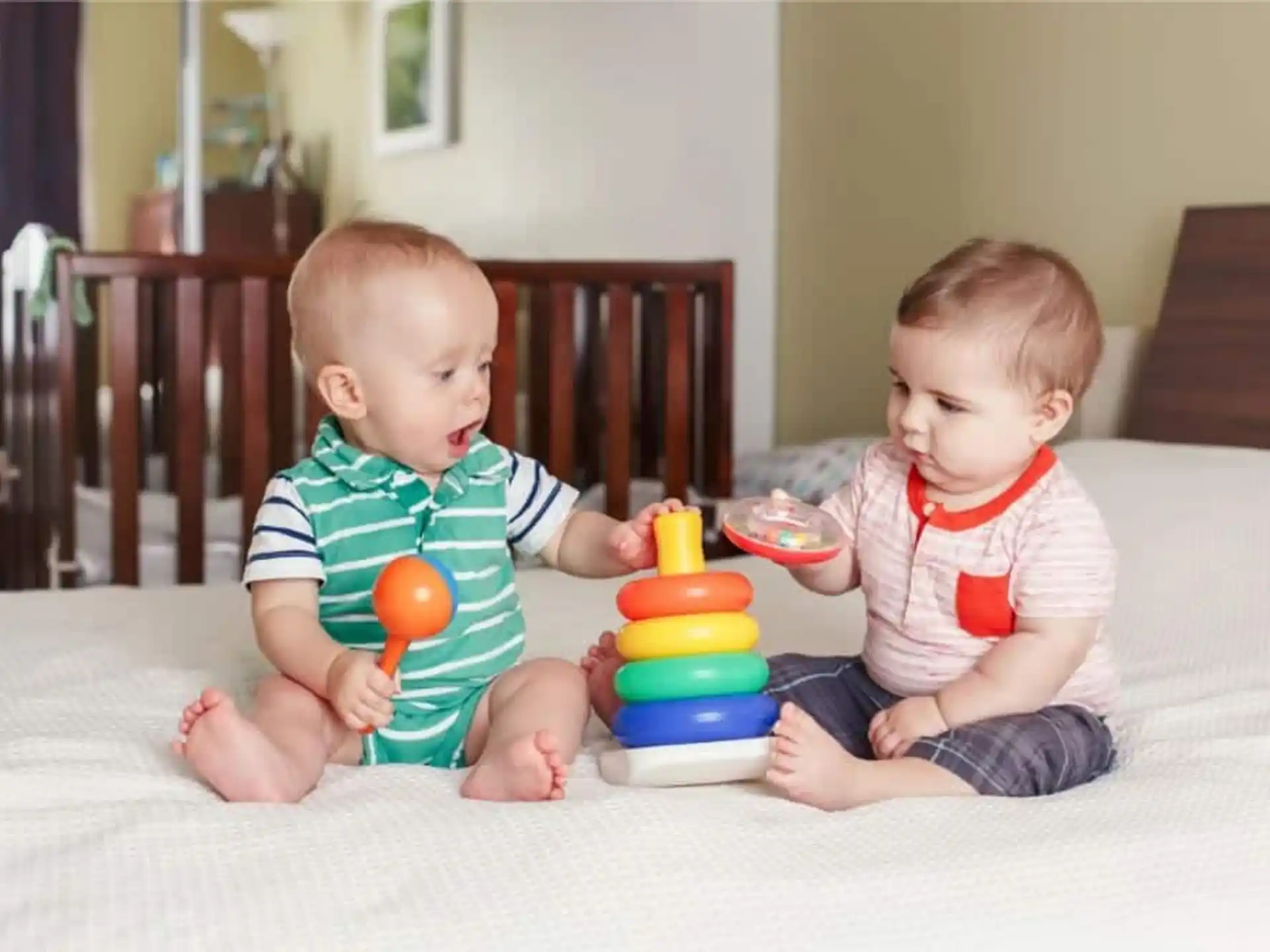 two babies sitting on a bed