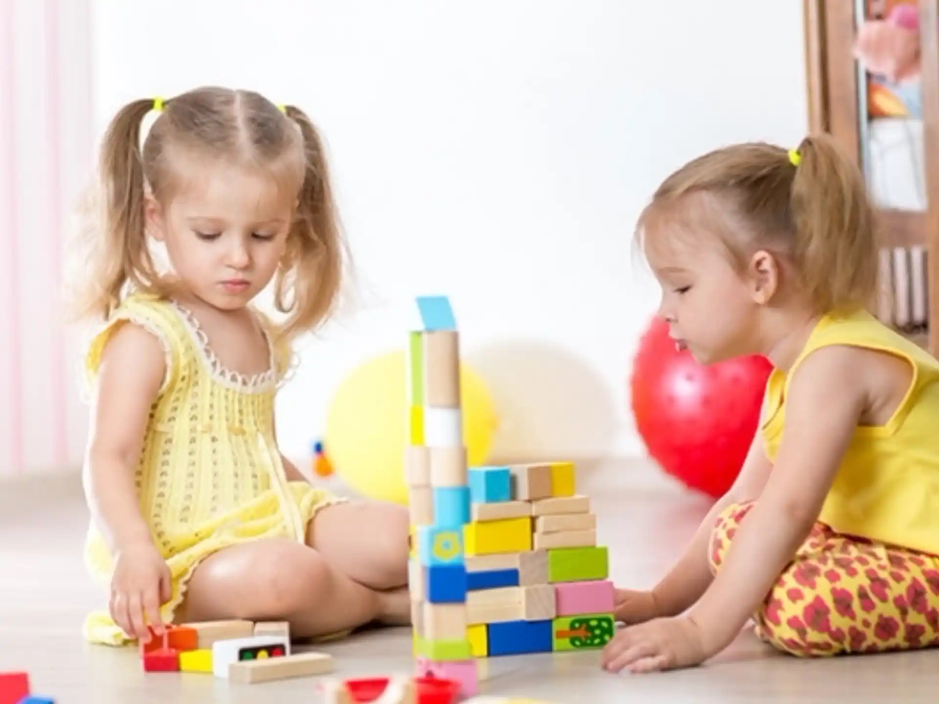 a couple of young girls playing with toys on the floor