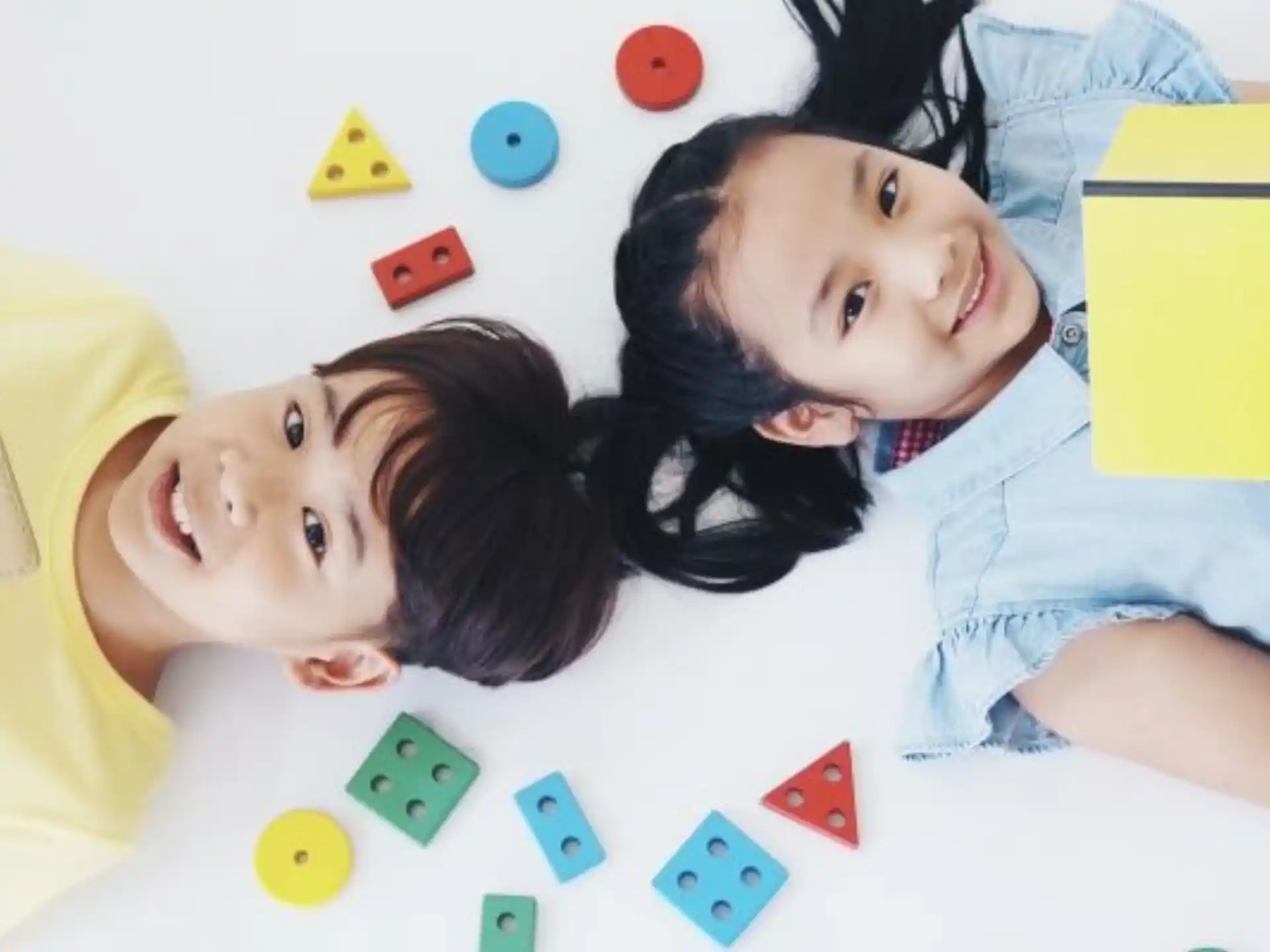 a couple of girls lying on the floor with a yellow laptop