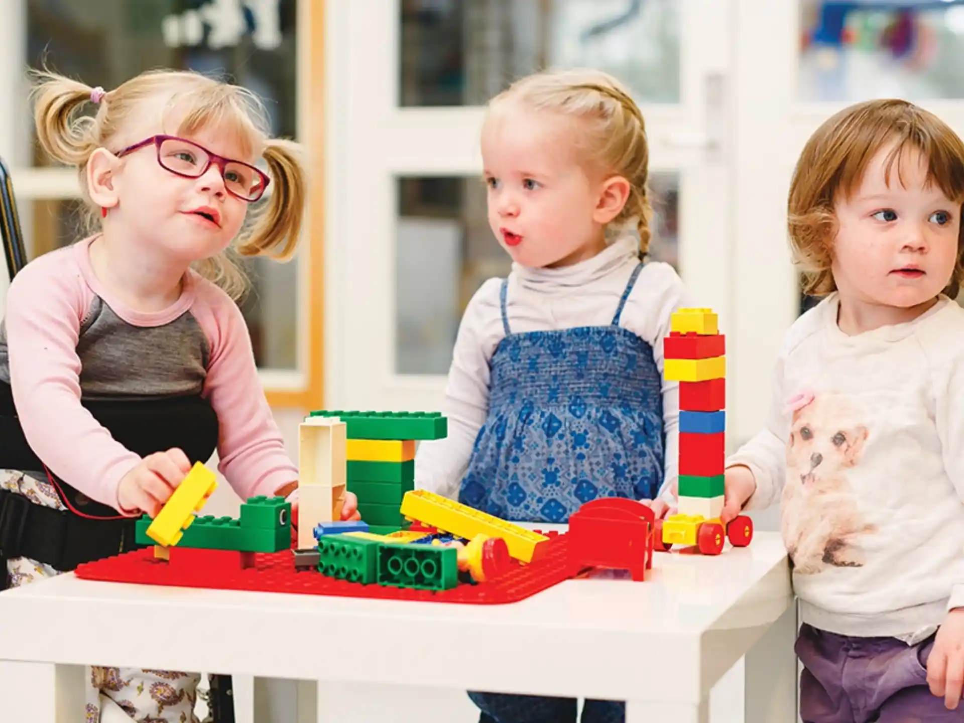 a group of children sitting at a table with toys