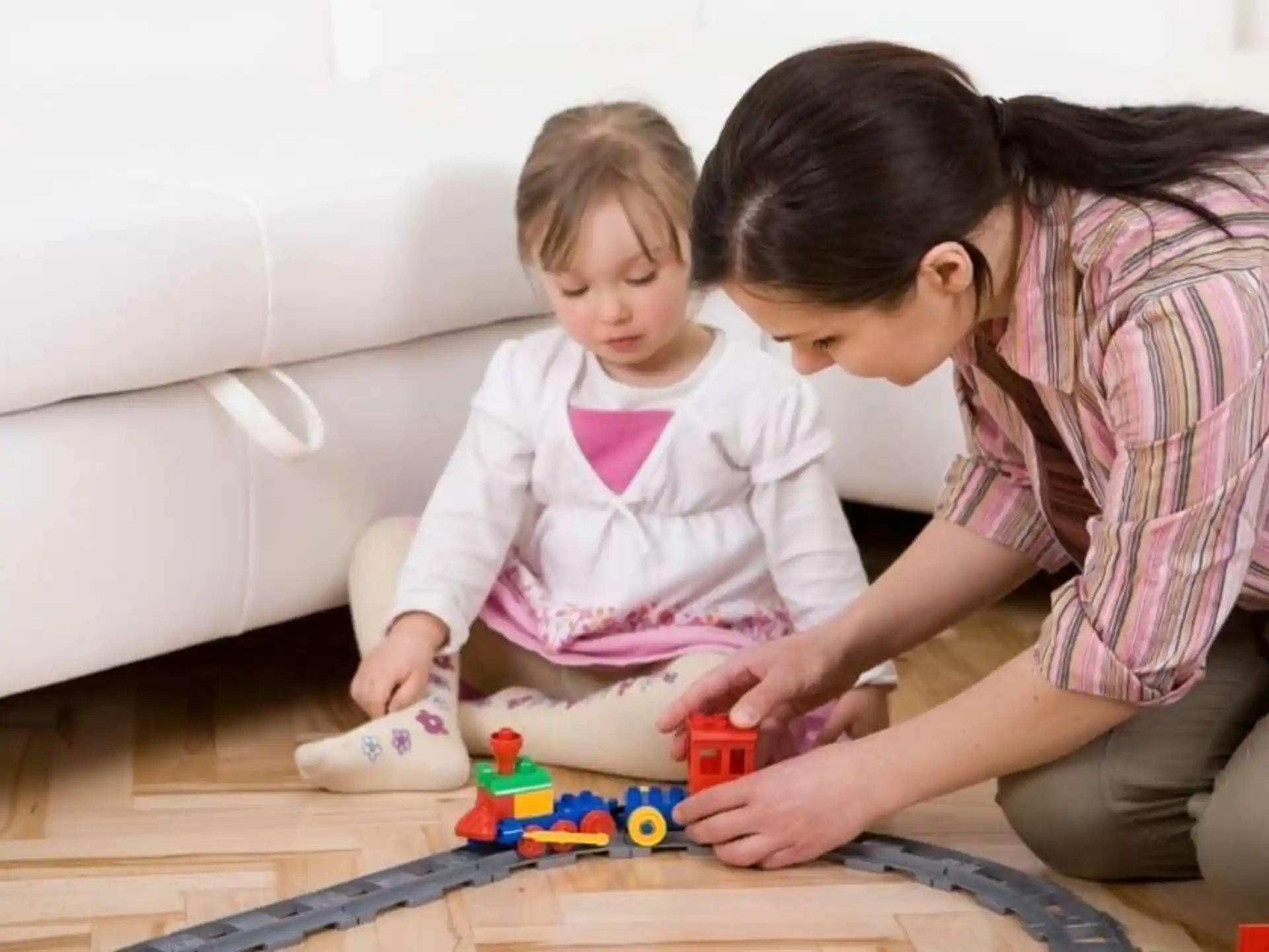 a person and a child playing with toys on the floor
