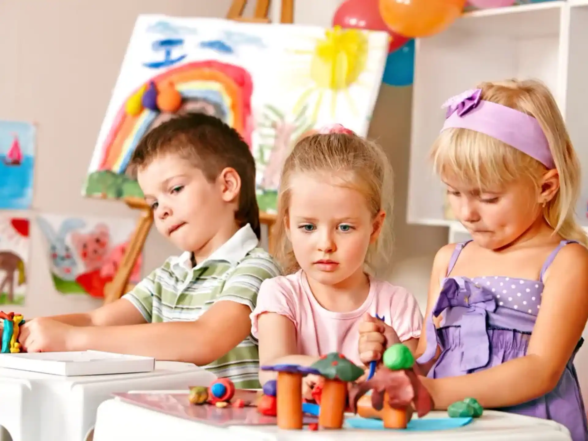 a group of children sitting at a table with a birthday hat