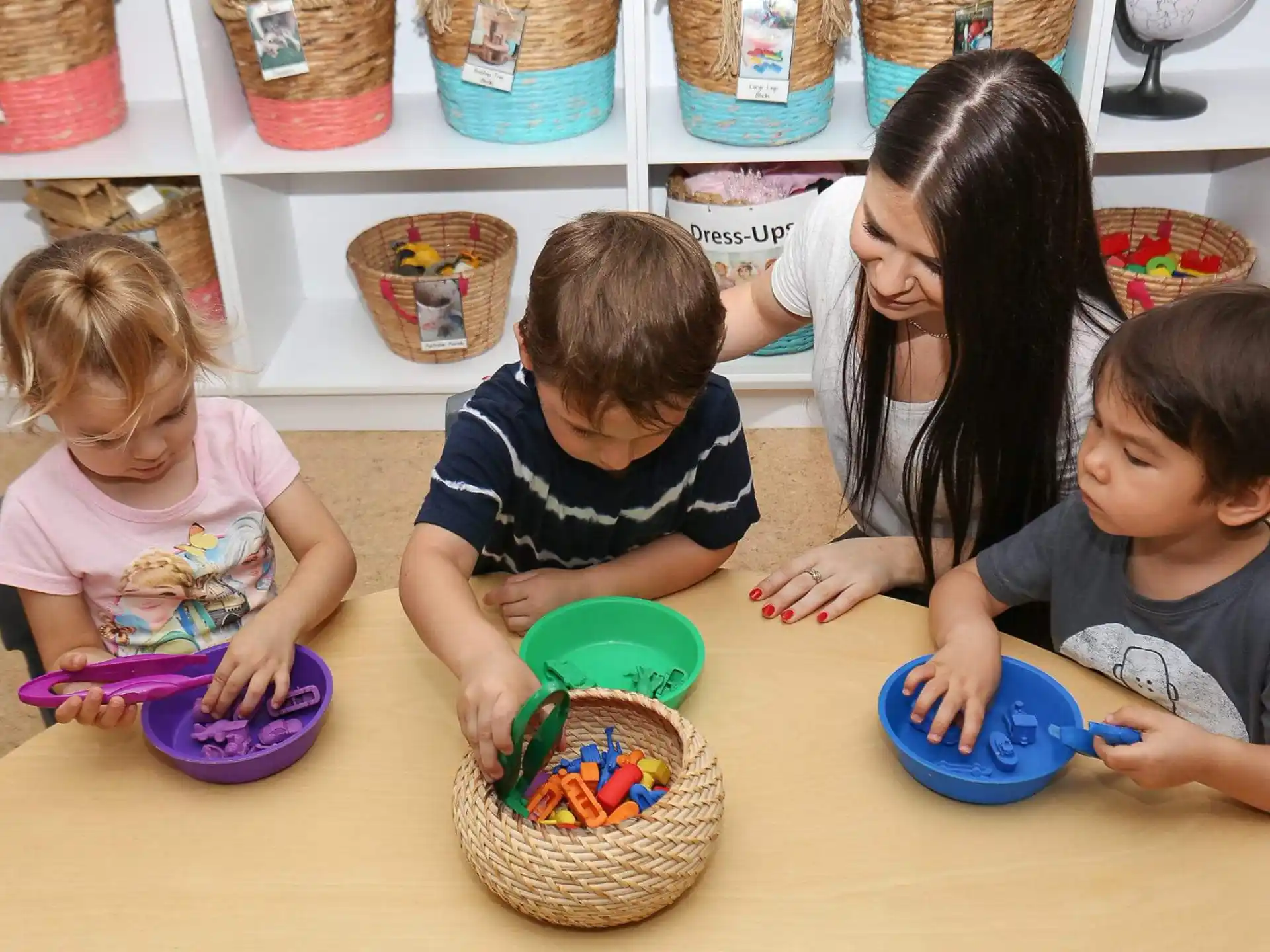 a group of children sitting at a table with baskets and bowls