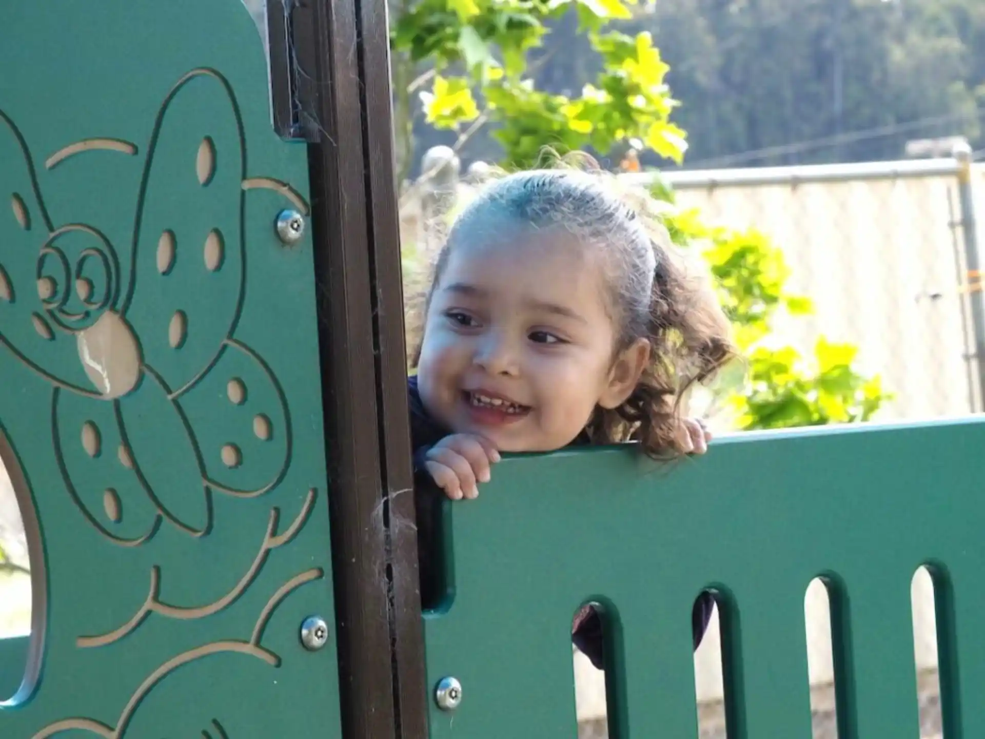 a girl smiling and leaning on a fence