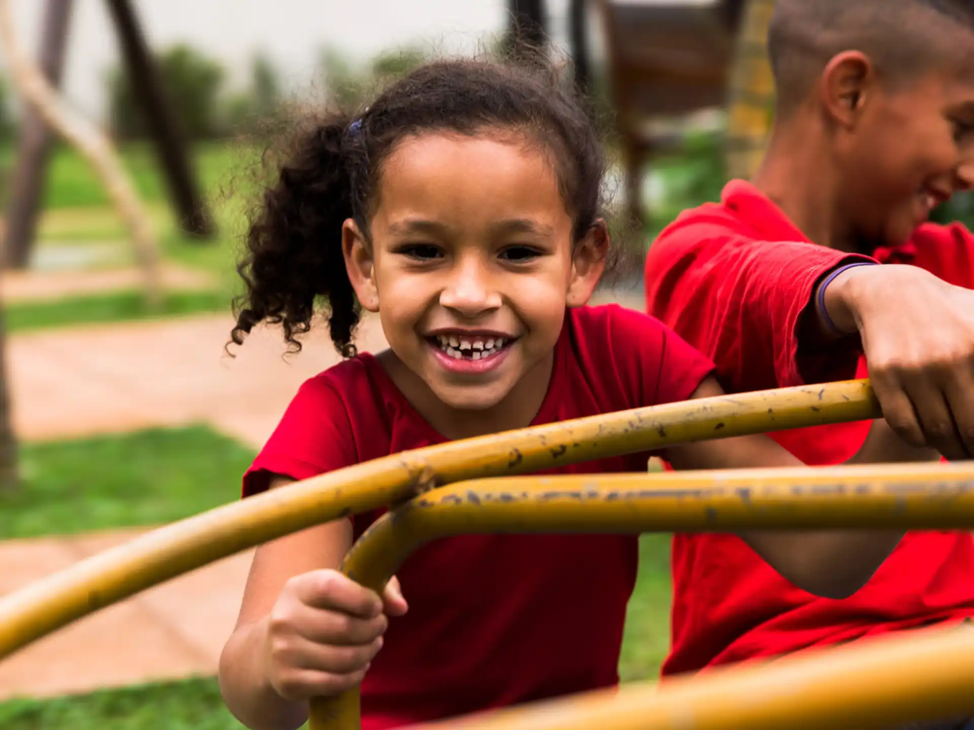 a boy and a person playing on a red playground toy