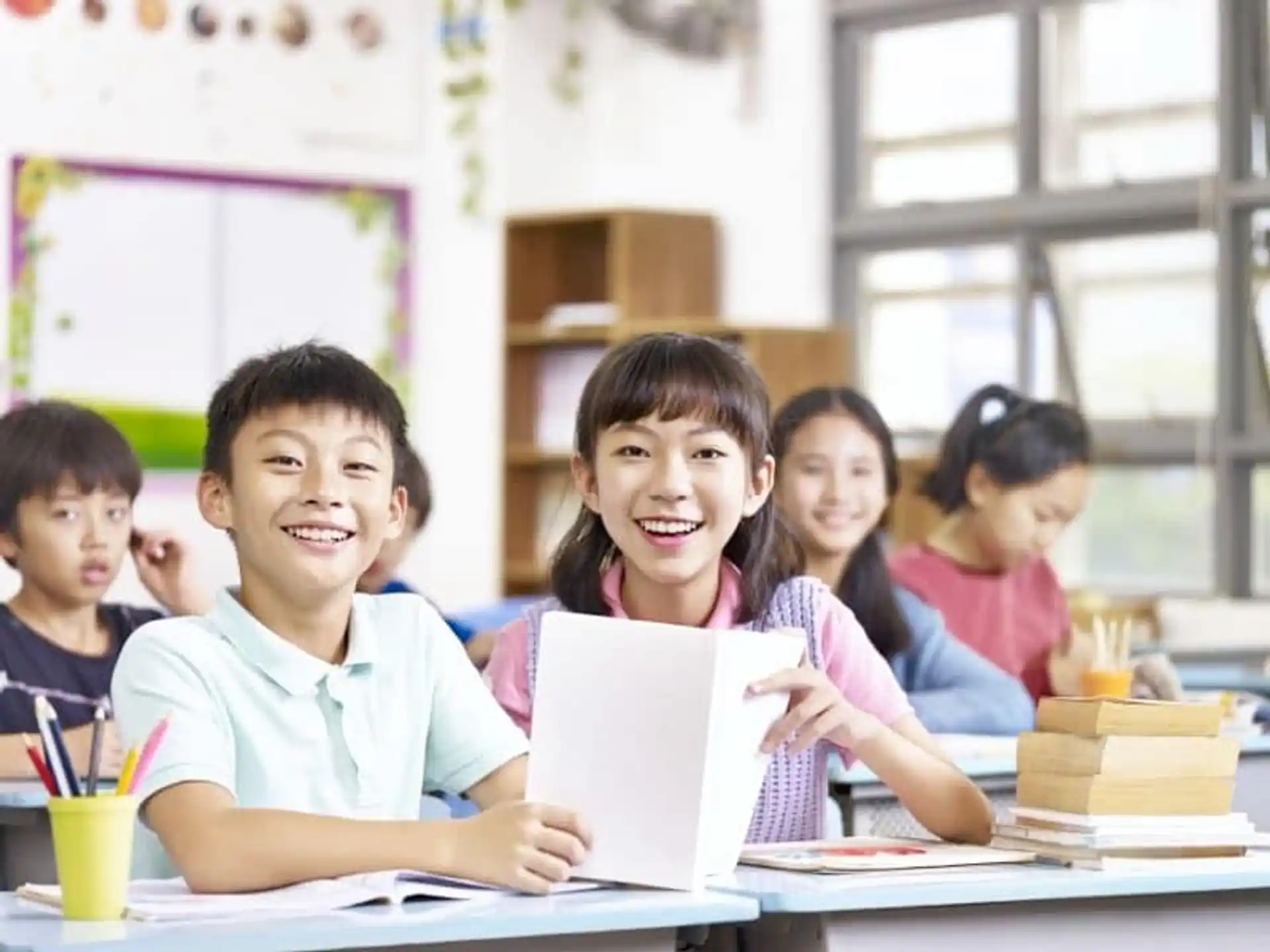 a group of children sitting at a table and smiling