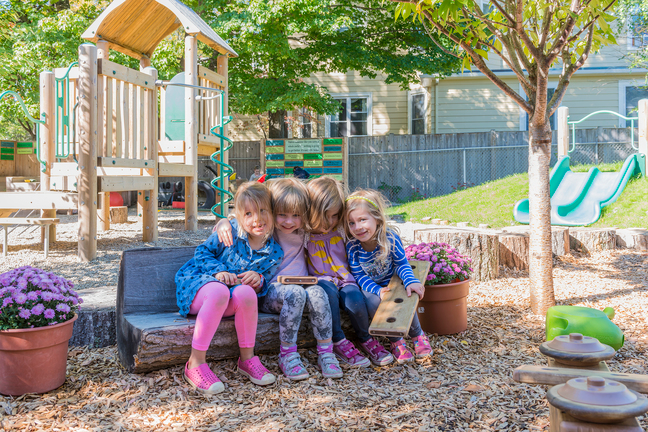 a group of girls sitting on a bench in a backyard