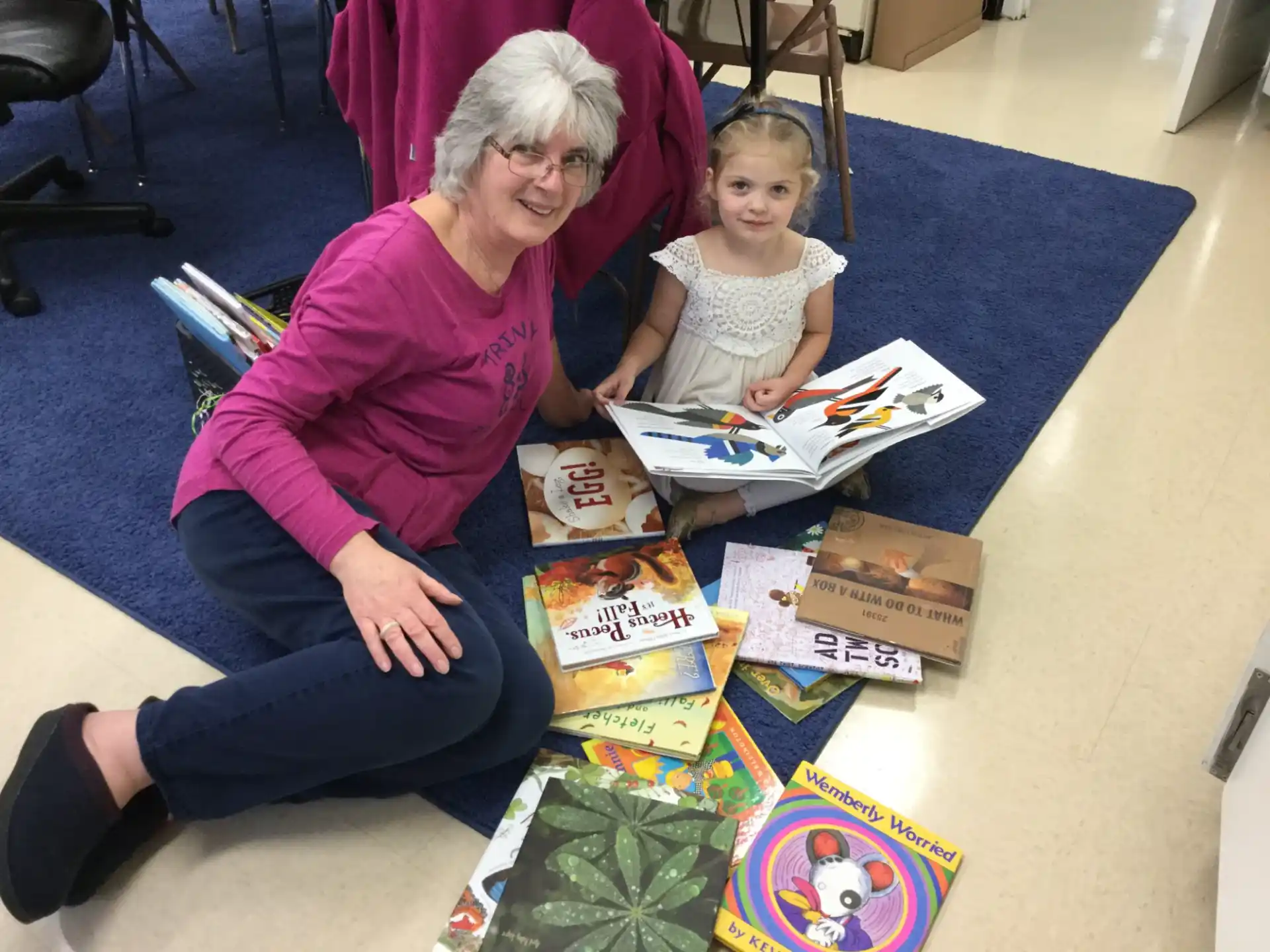 a person and a girl sitting at a table with boxes and a book