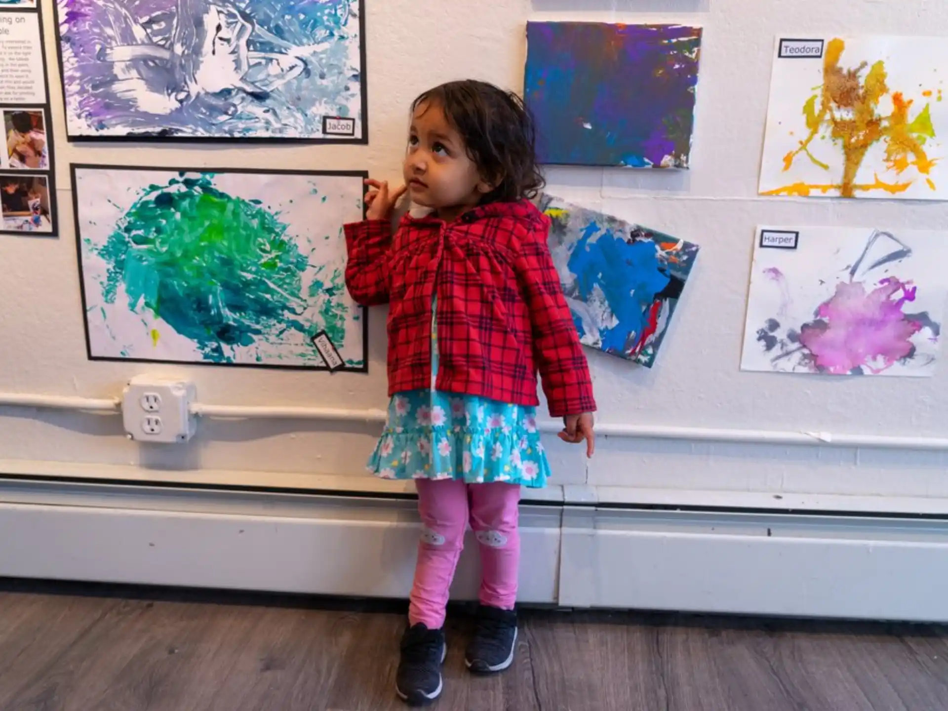 a girl standing in front of a wall with art on it