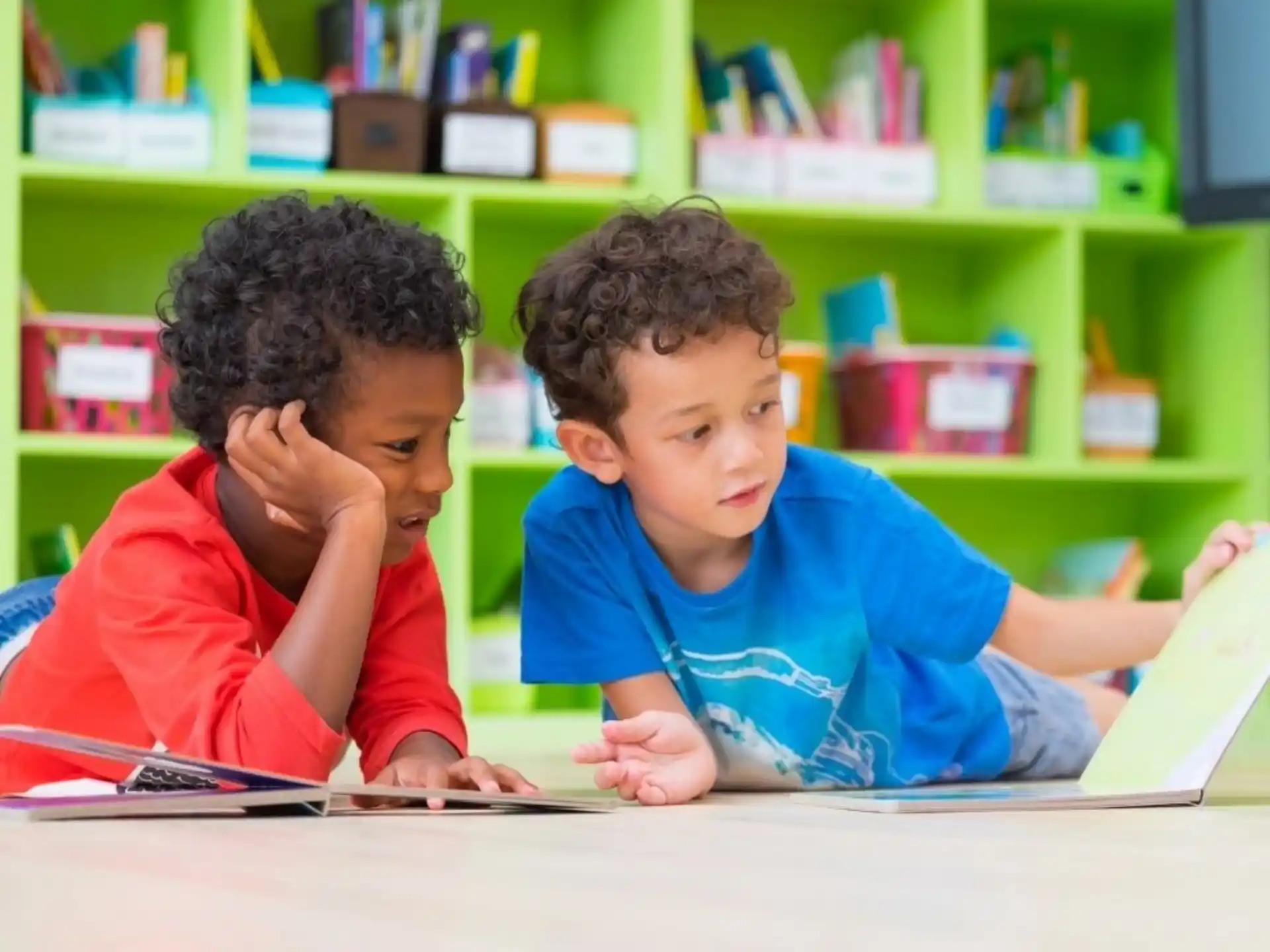 a couple of young boys sitting at a table in a library