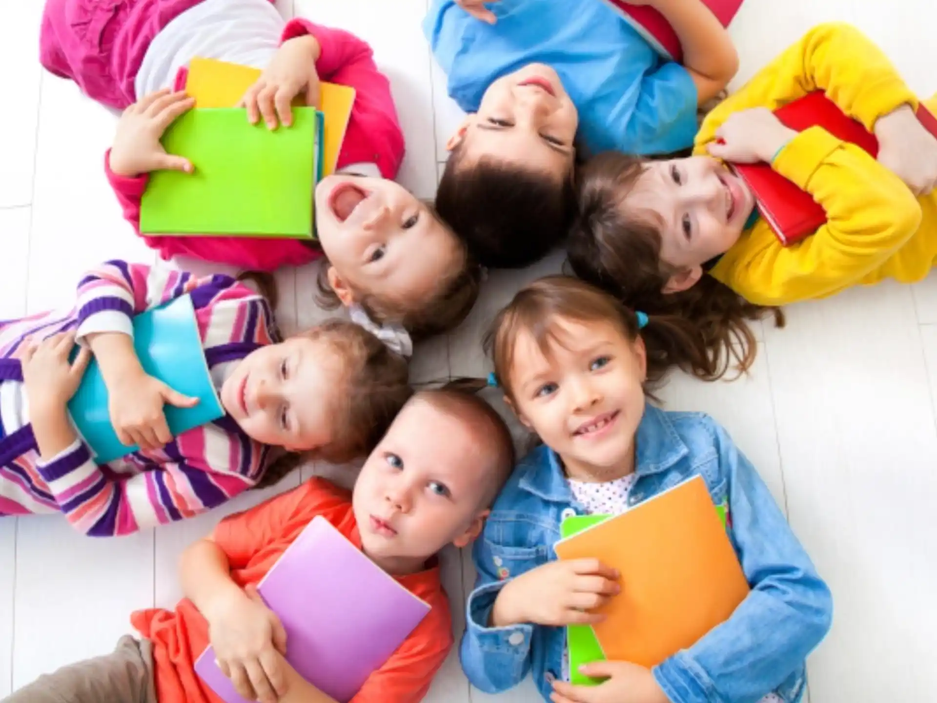 a group of children lying on the floor and holding books