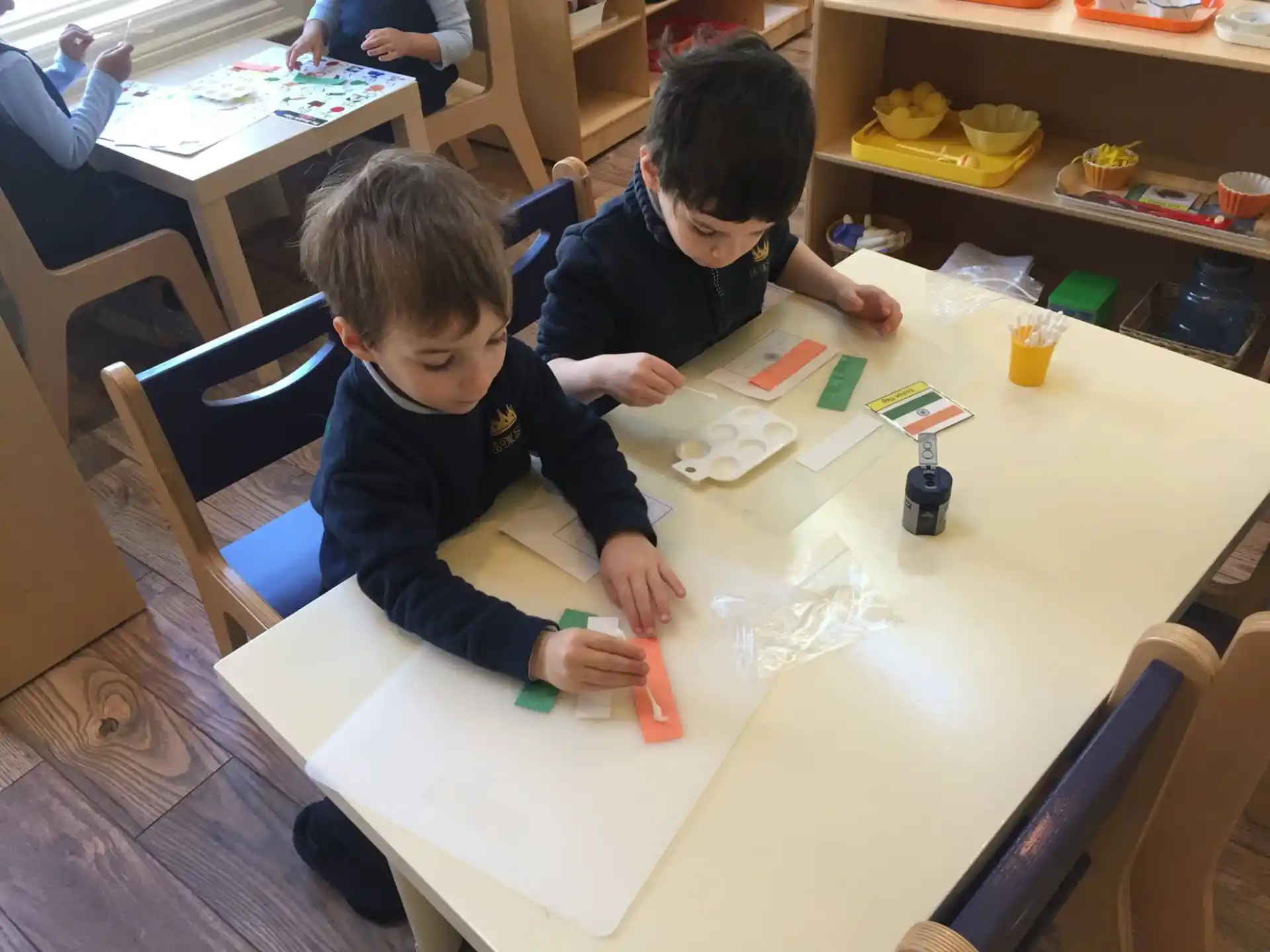 a couple of boys sitting at a table with a toy