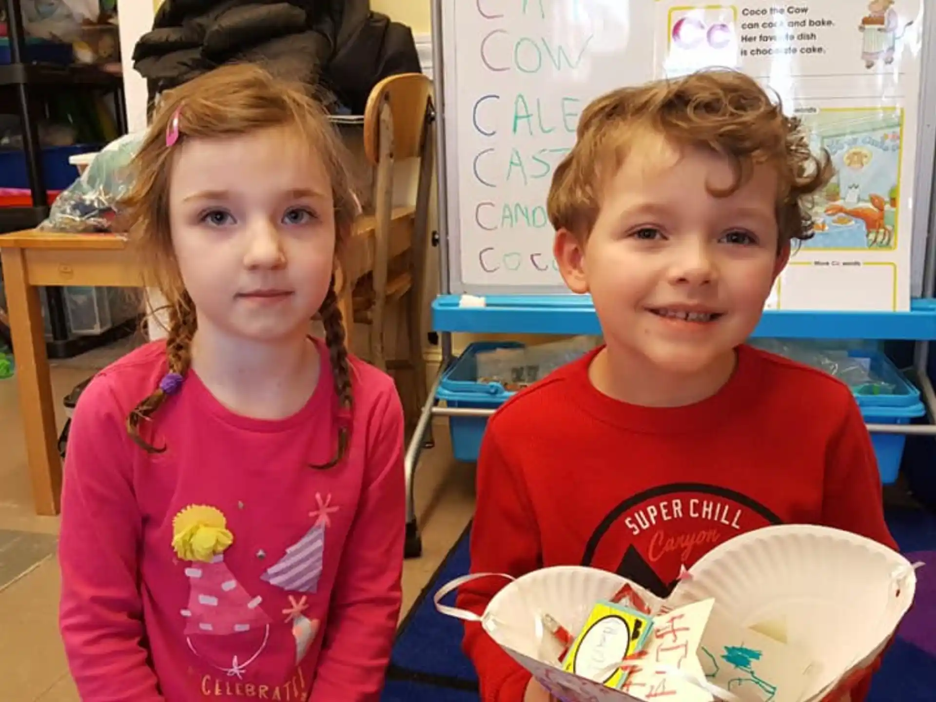 a couple of children sitting at a table with food