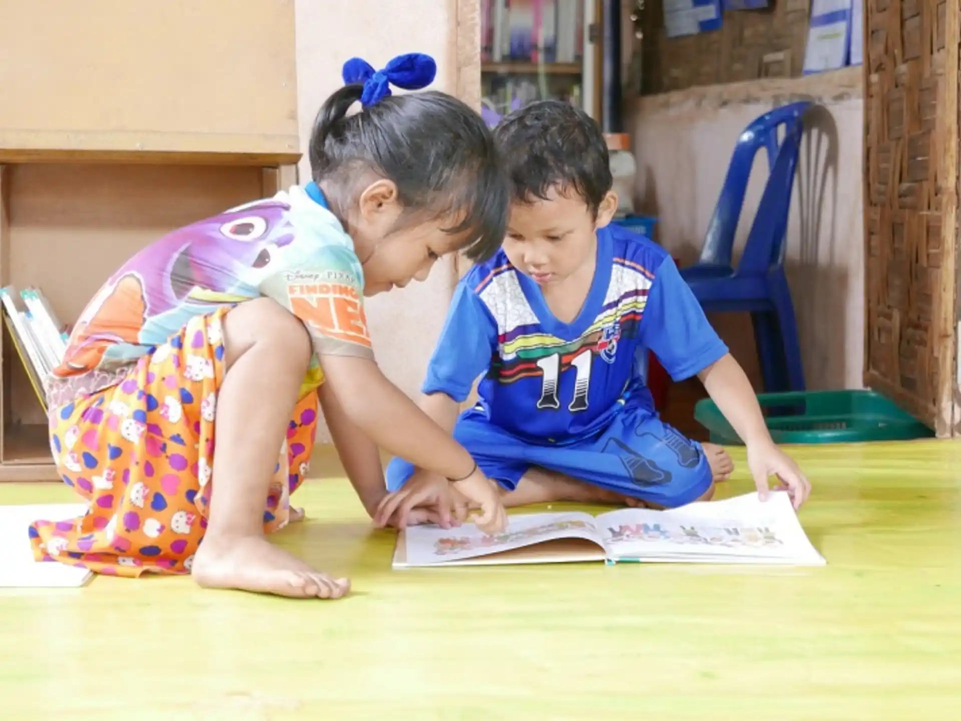 a couple of children sitting at a table looking at a book