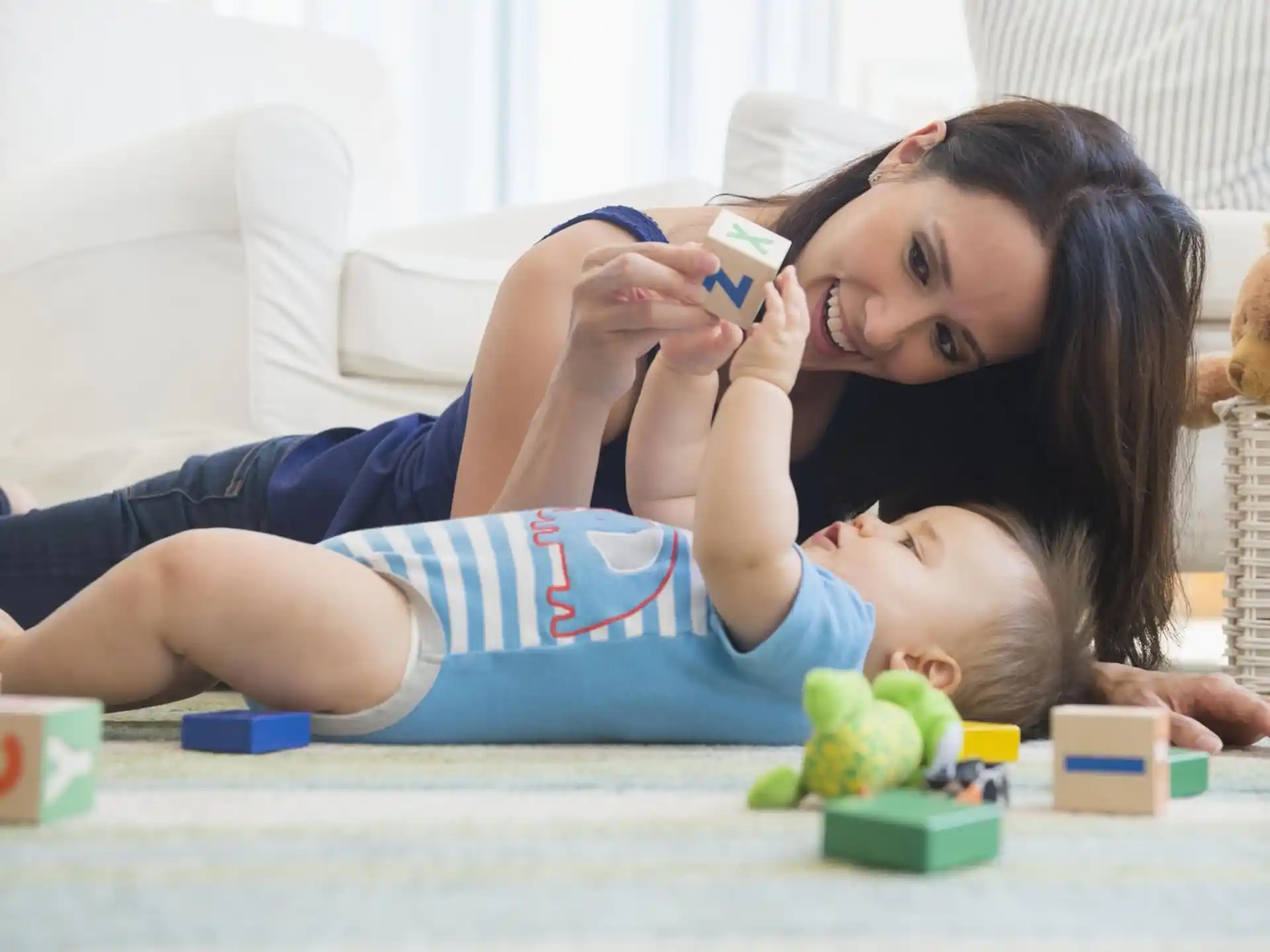 a woman lying on the floor with a baby on her chest