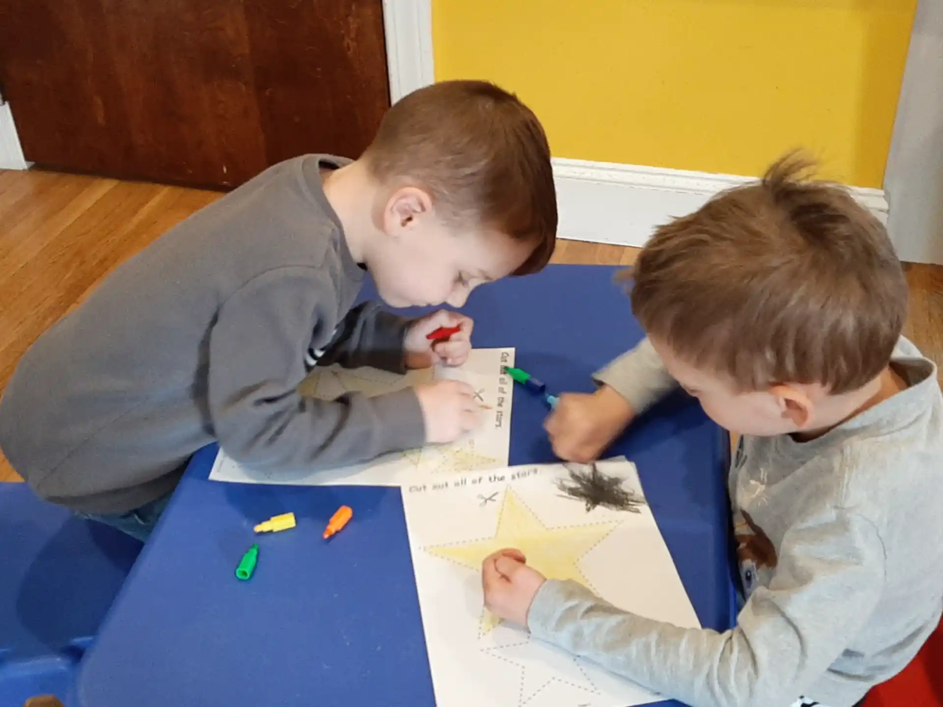 a couple of boys sitting at a table looking at a paper