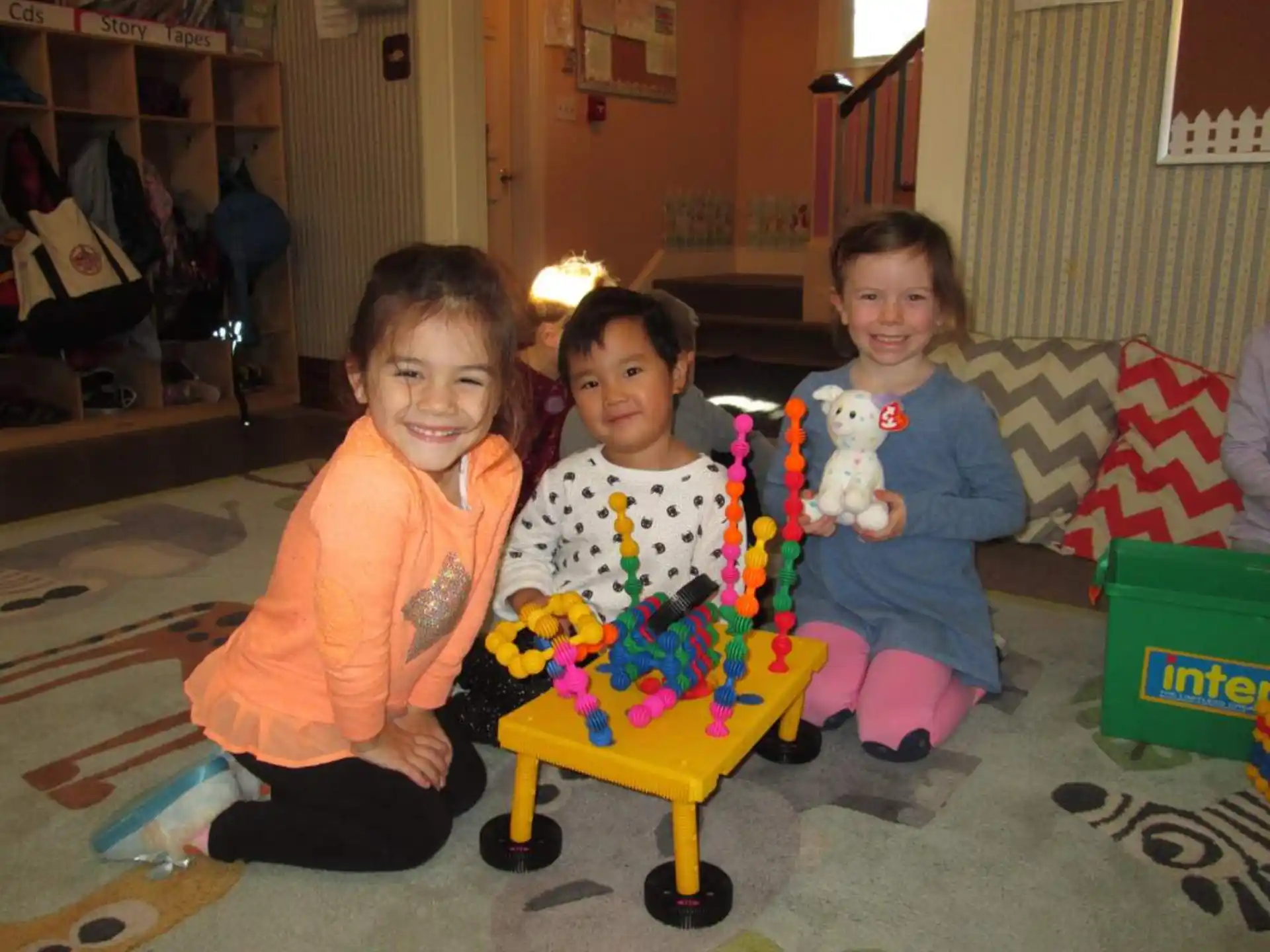 a group of children sitting on the floor with a toy car