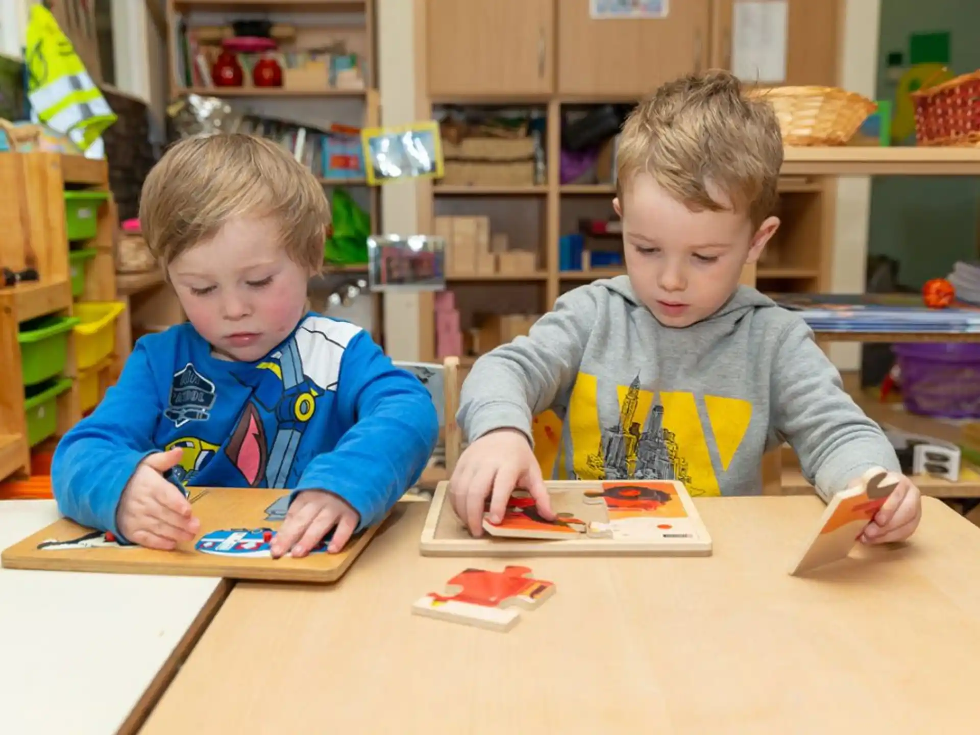 a couple of boys sitting at a table looking at a book
